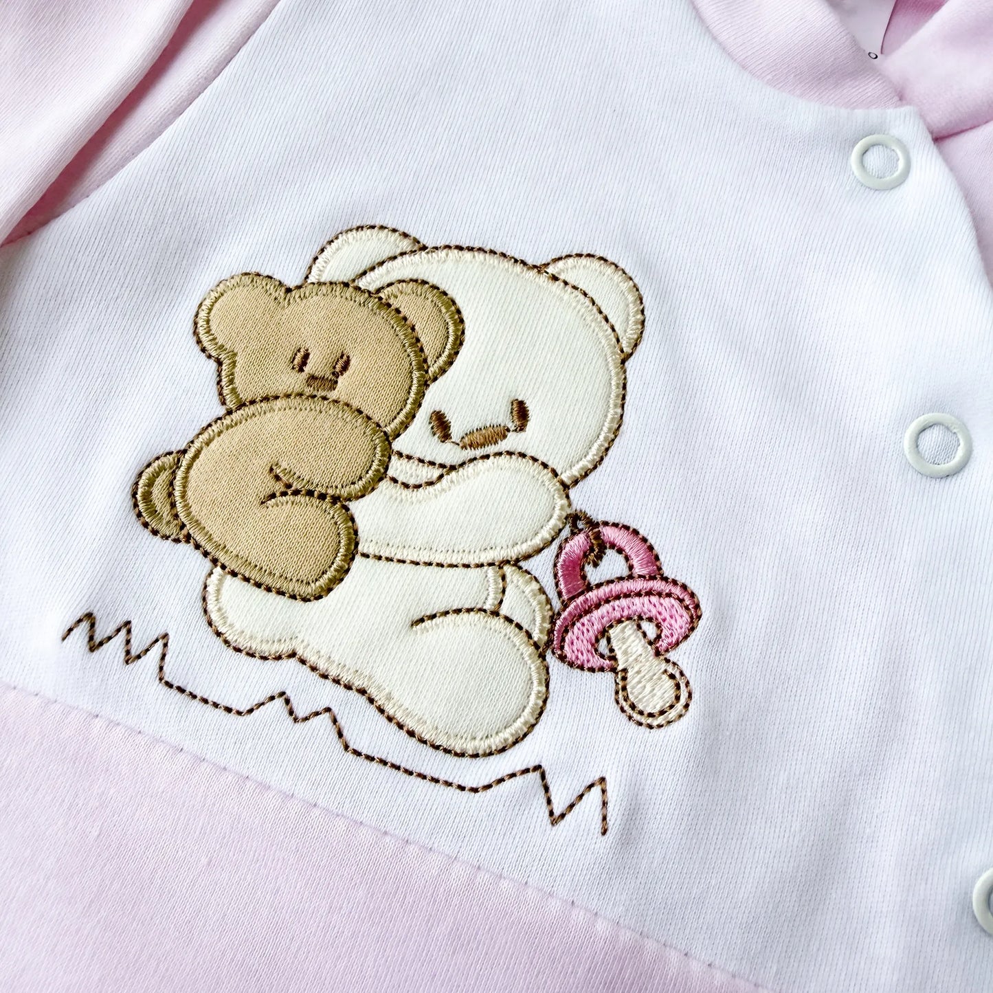 Pormenor de babygrow de algodão com motivo ursinho às cavalitas rosa