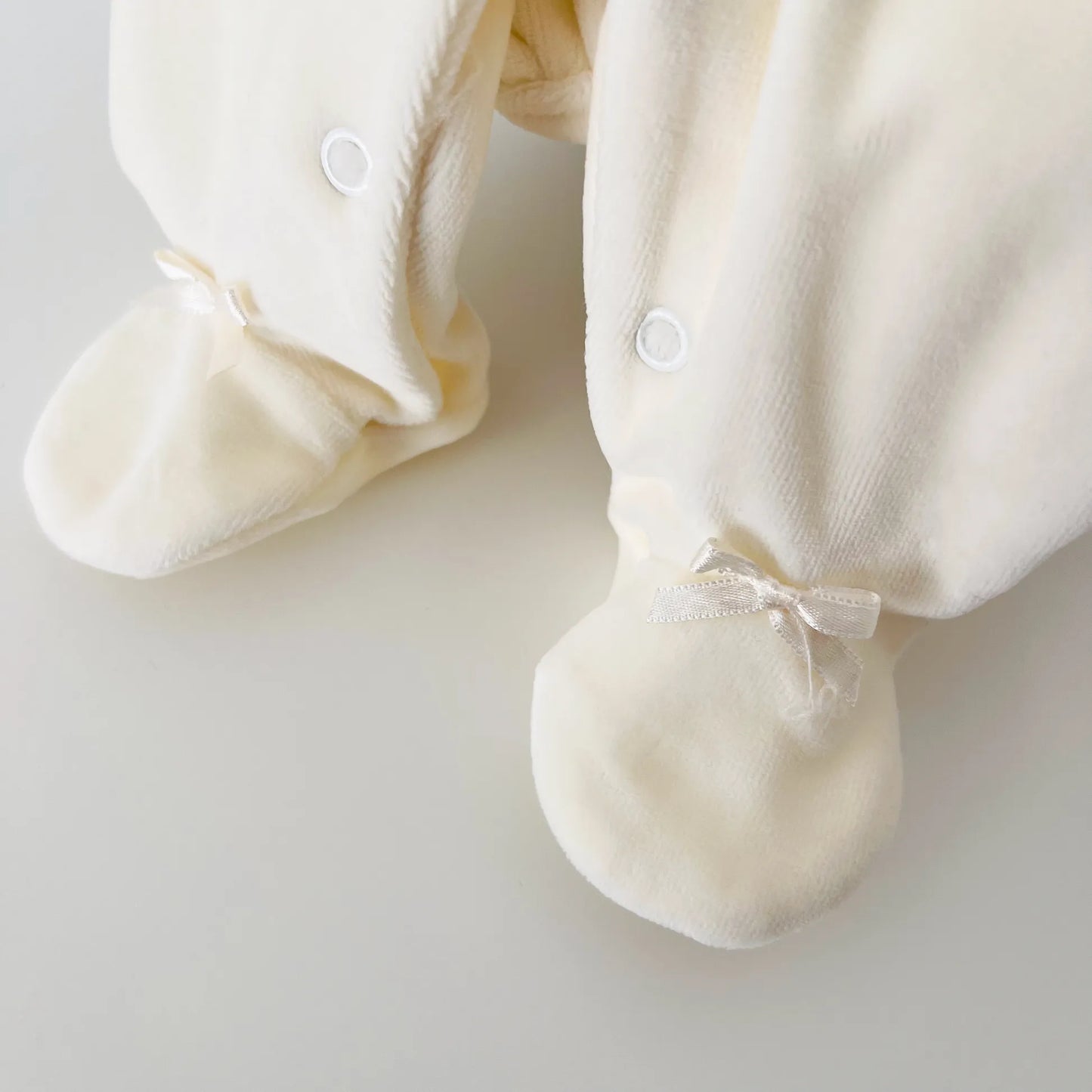 Pormenor de babygrow de menina com gola redonda e bordado losangos pérola