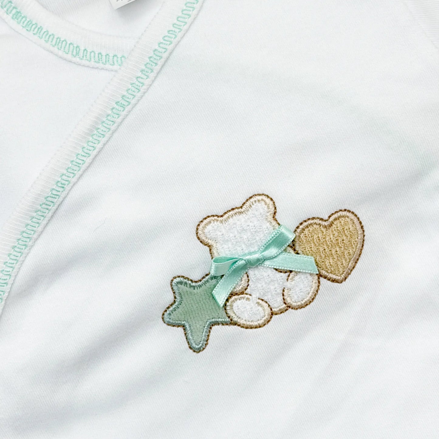 Pormenor de body de trespasse com collant com motivo ursinho entre estrela e coração verde