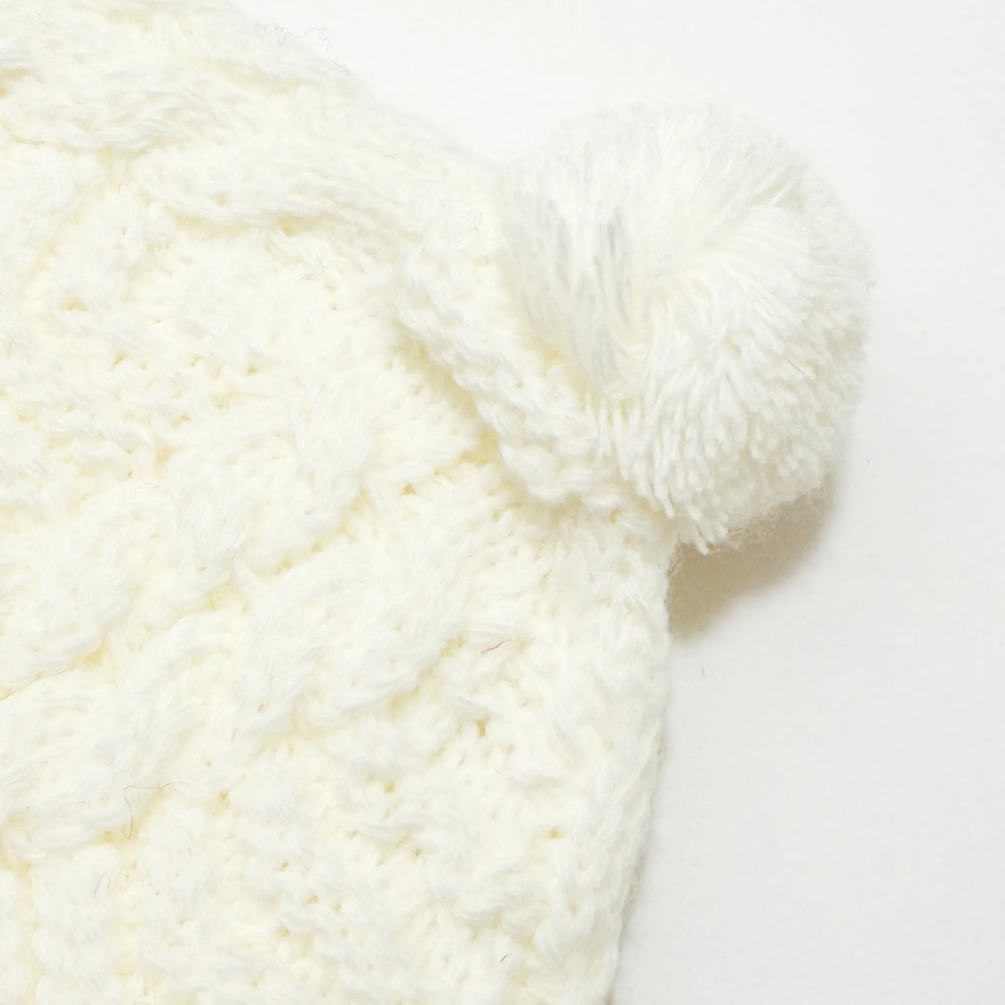 Pormenor de gorro de malha tricotada com pompom pérola