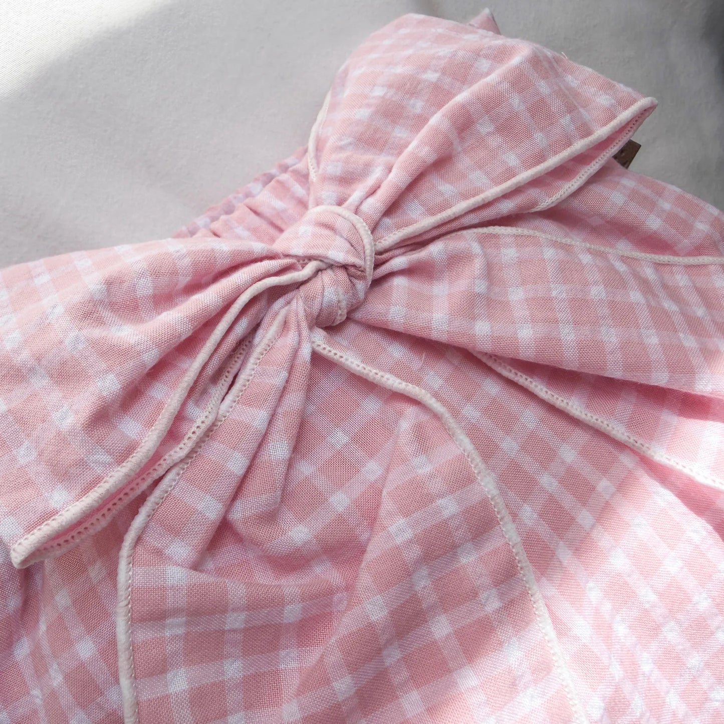 Pormenor de tapa-fraldas de menina em tecido com laço na frente e folhos rosa