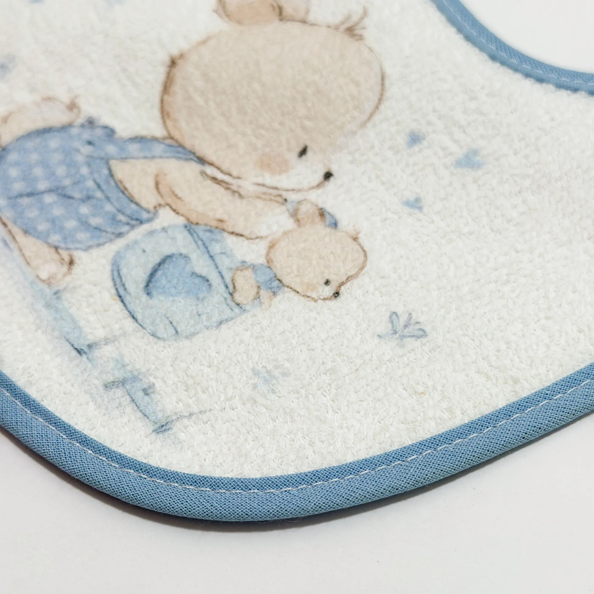 Pormenor de babete impermeável com motivo coelhinho na cesta azul