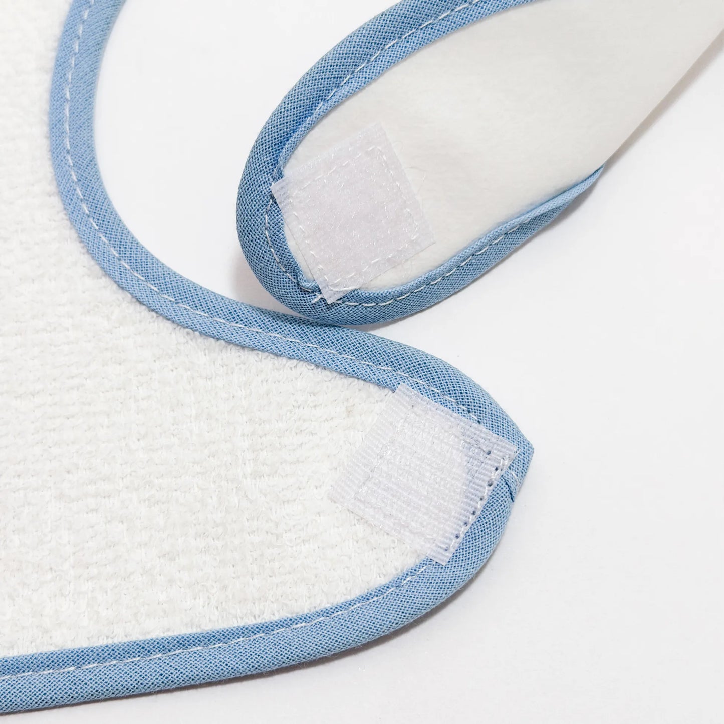 Pormenor de babete impermeável com motivo coelhinho na cesta azul