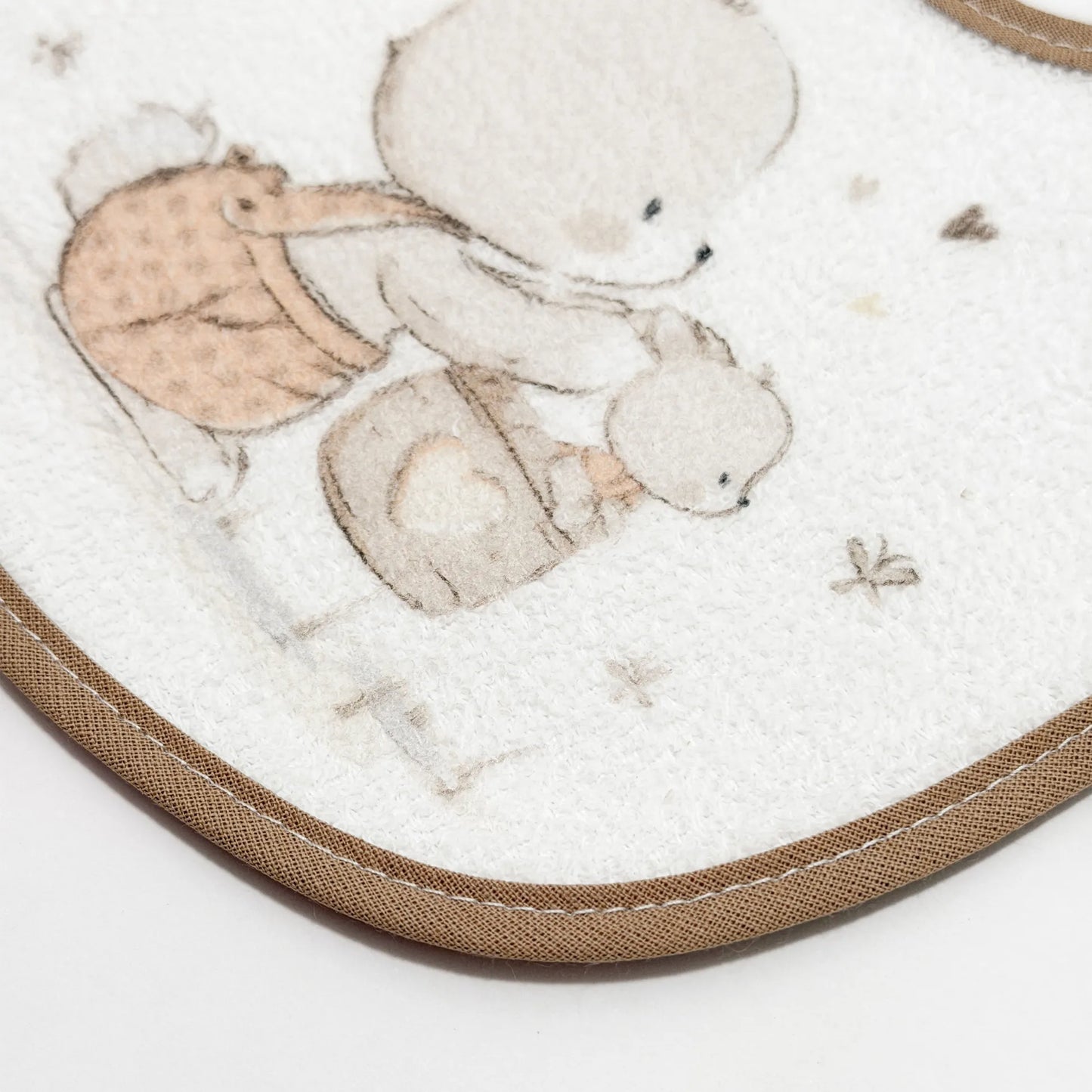 Pormenor de babete impermeável com motivo coelhinho na cesta bege