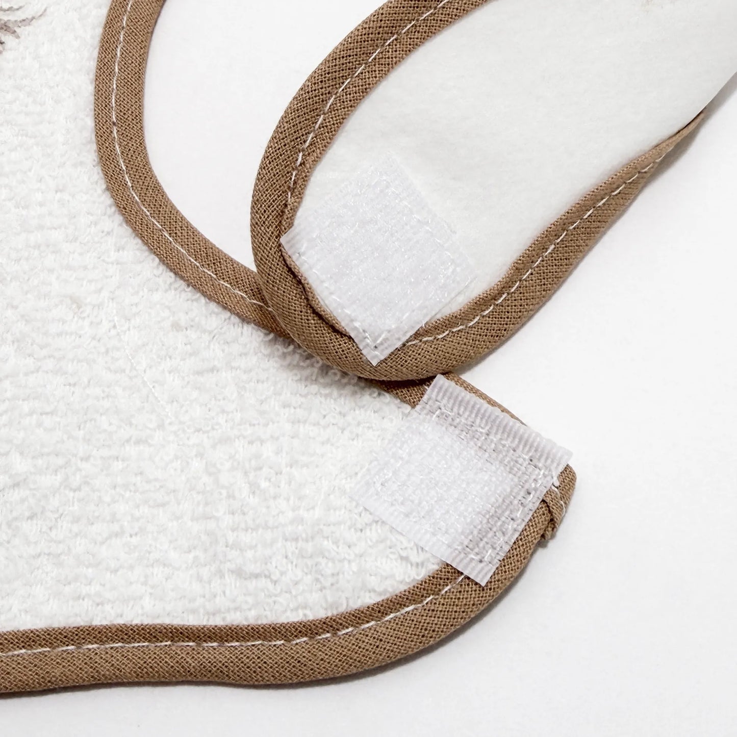 Pormenor de babete impermeável com motivo coelhinho na cesta bege