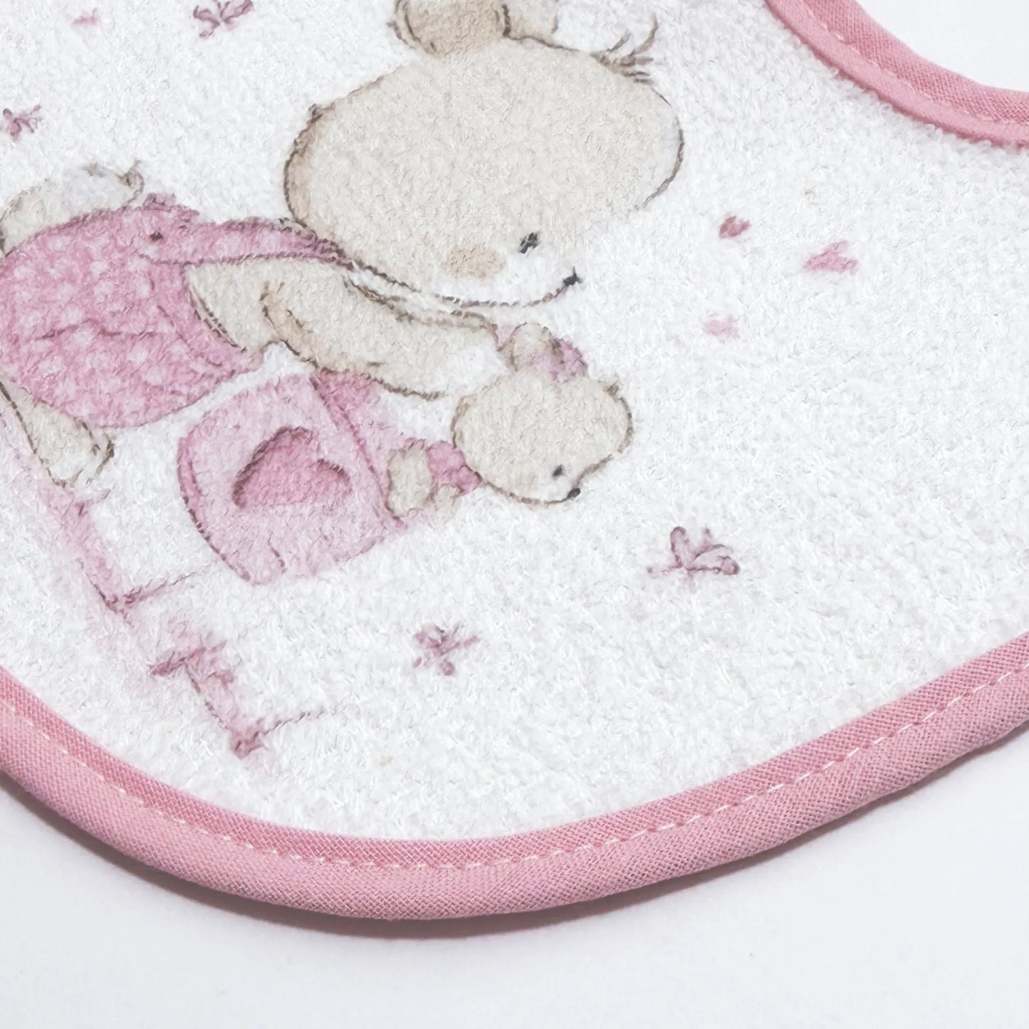 Pormenor de babete impermeável com motivo coelhinho na cesta rosa