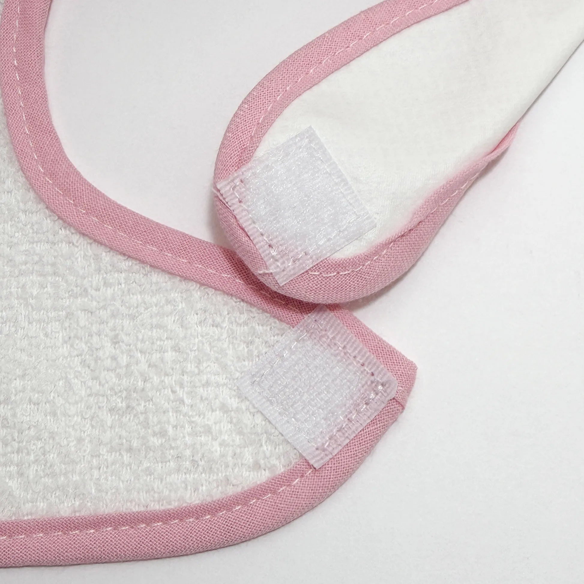 Pormenor de babete impermeável com motivo coelhinho na cesta rosa