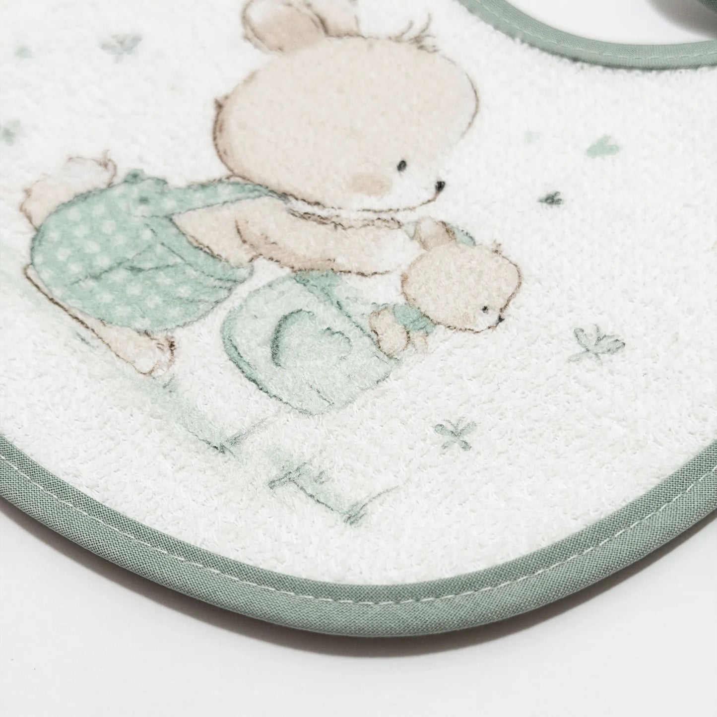 Pormenor de babete impermeável com motivo coelhinho na cesta verde