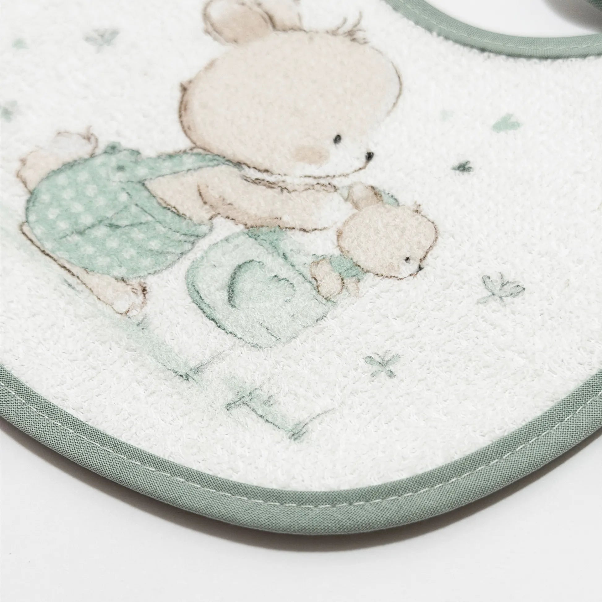 Pormenor de babete impermeável com motivo coelhinho na cesta verde