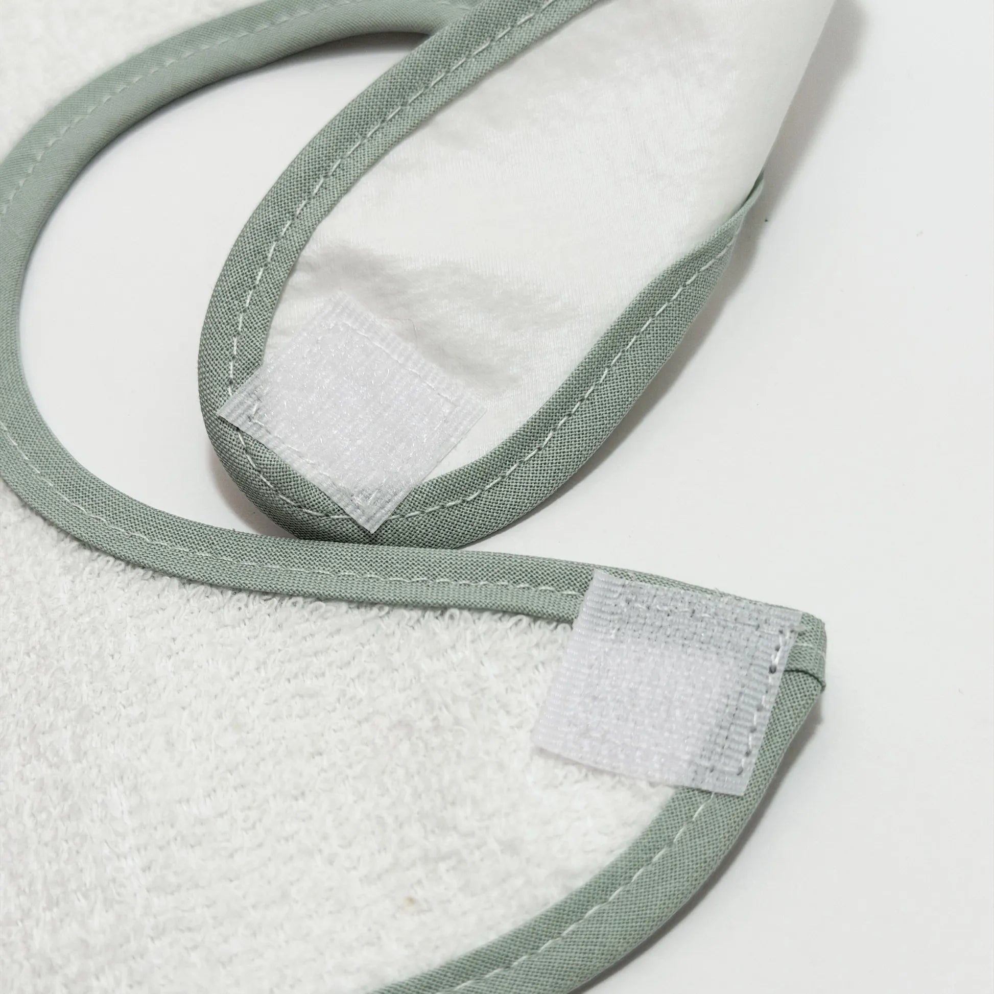 Pormenor de babete impermeável com motivo coelhinho na cesta verde