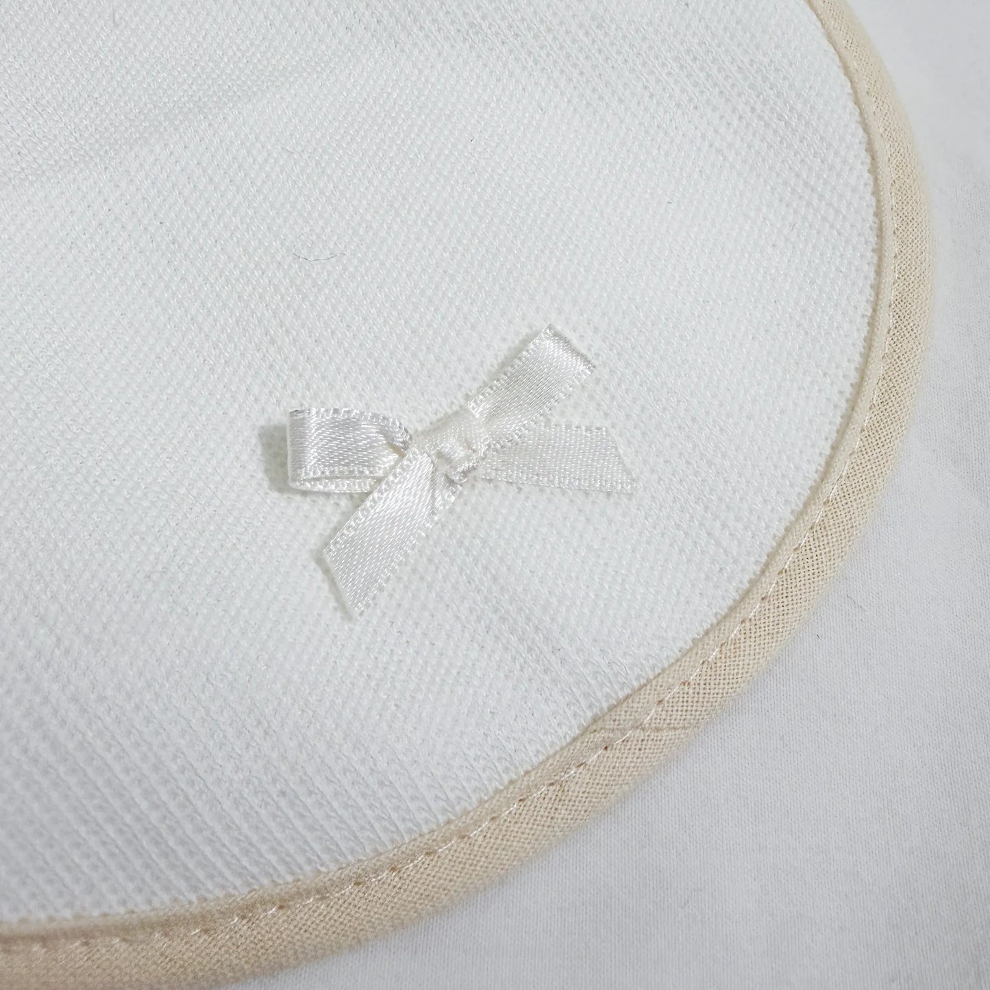 Pormenor de babete liso com lacinho pérola