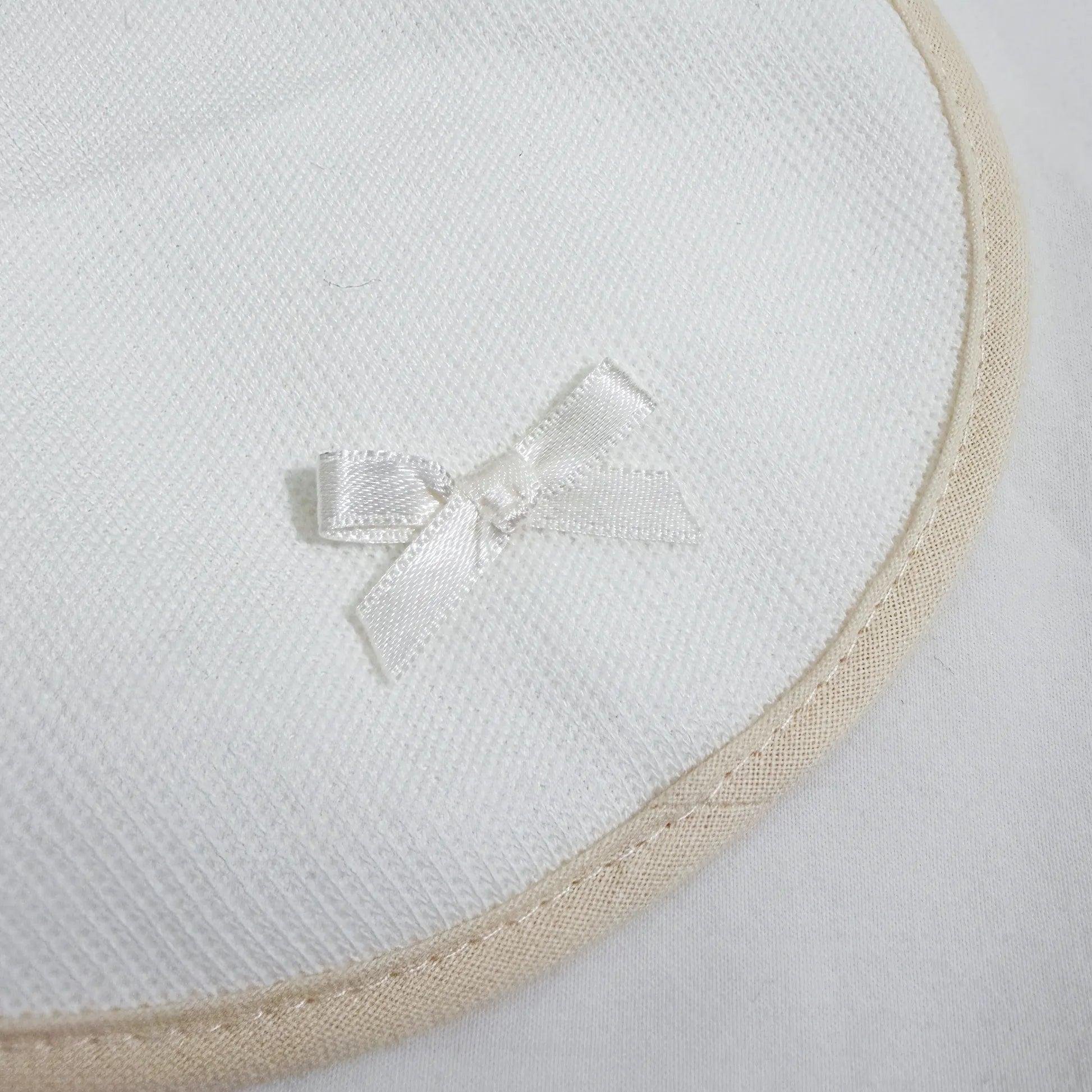 Pormenor de babete liso com lacinho pérola