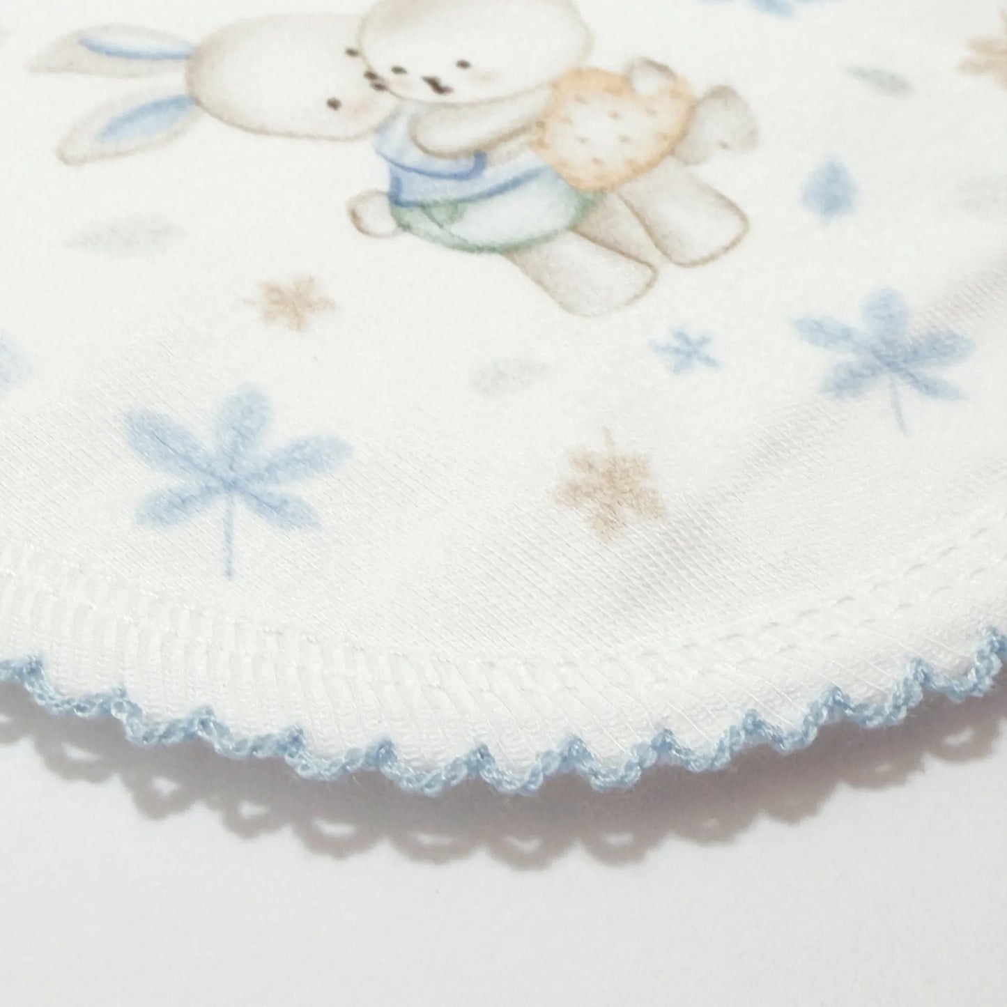 Pormenor de babete com motivo coelhinhos abraçados azul