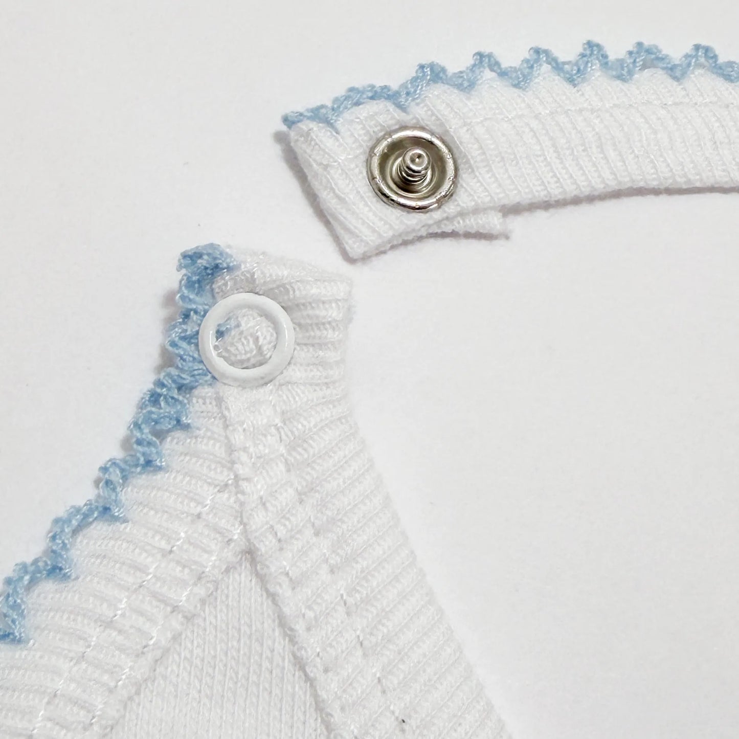 Pormenor de babete com motivo coelhinhos abraçados azul