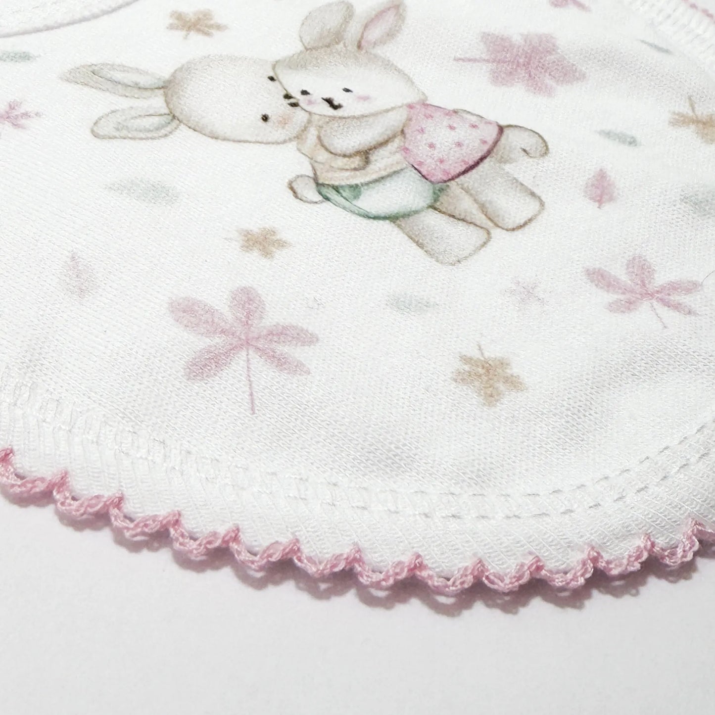 Pormenor de babete com motivo coelhinhos abraçados rosa