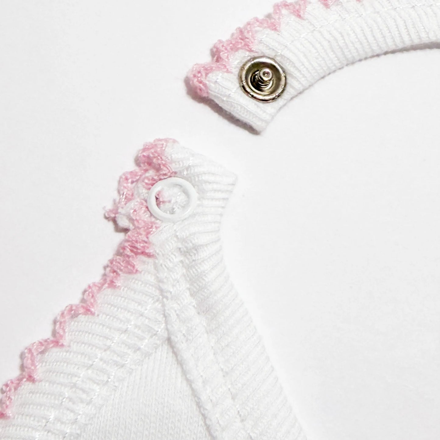 Pormenor de babete com motivo coelhinhos abraçados rosa