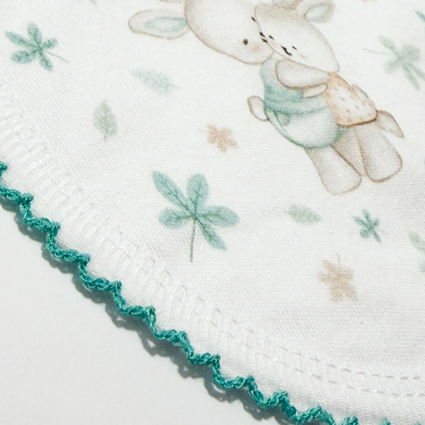 Pormenor de babete com motivo coelhinhos abraçados verde