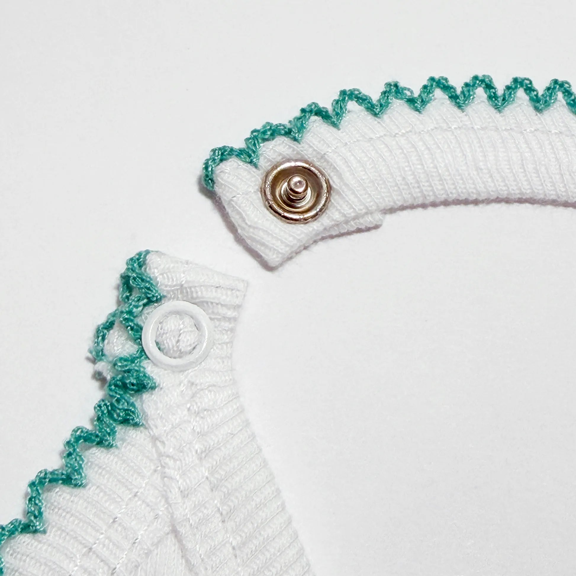 Pormenor de babete com motivo coelhinhos abraçados verde