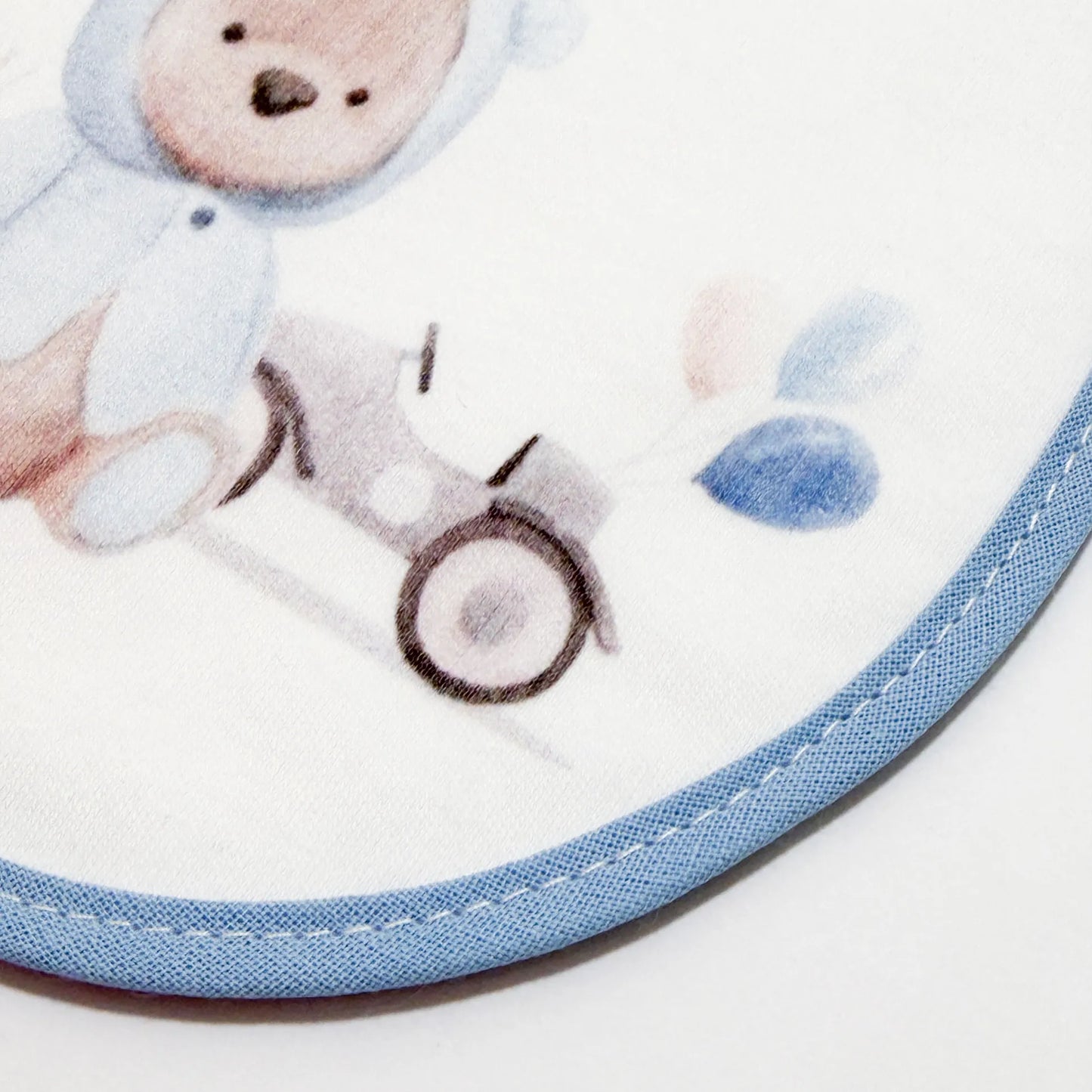 Pormenor de babete com motivo ursinho com capuz azul