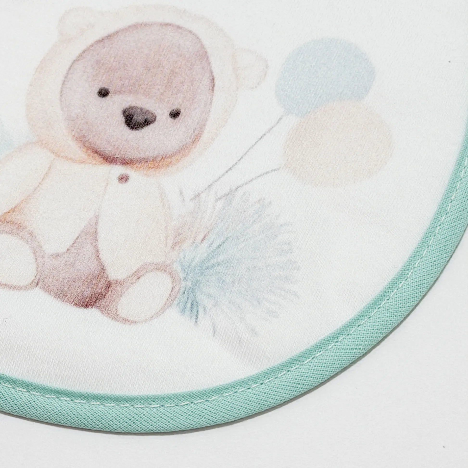 Pormenor de babete com motivo ursinho com capuz verde