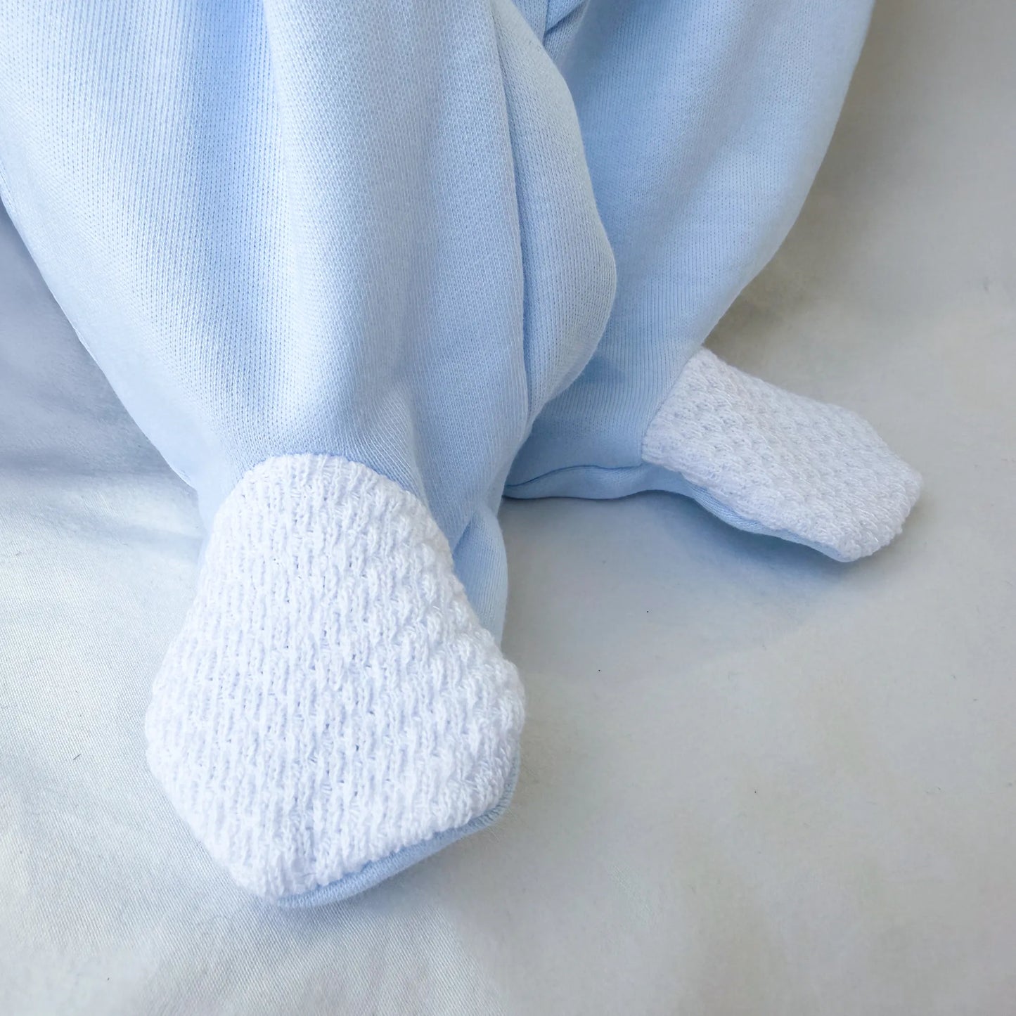 Pormenor de babygrow de algodão com motivo coelhinho e ursinho com livro azul