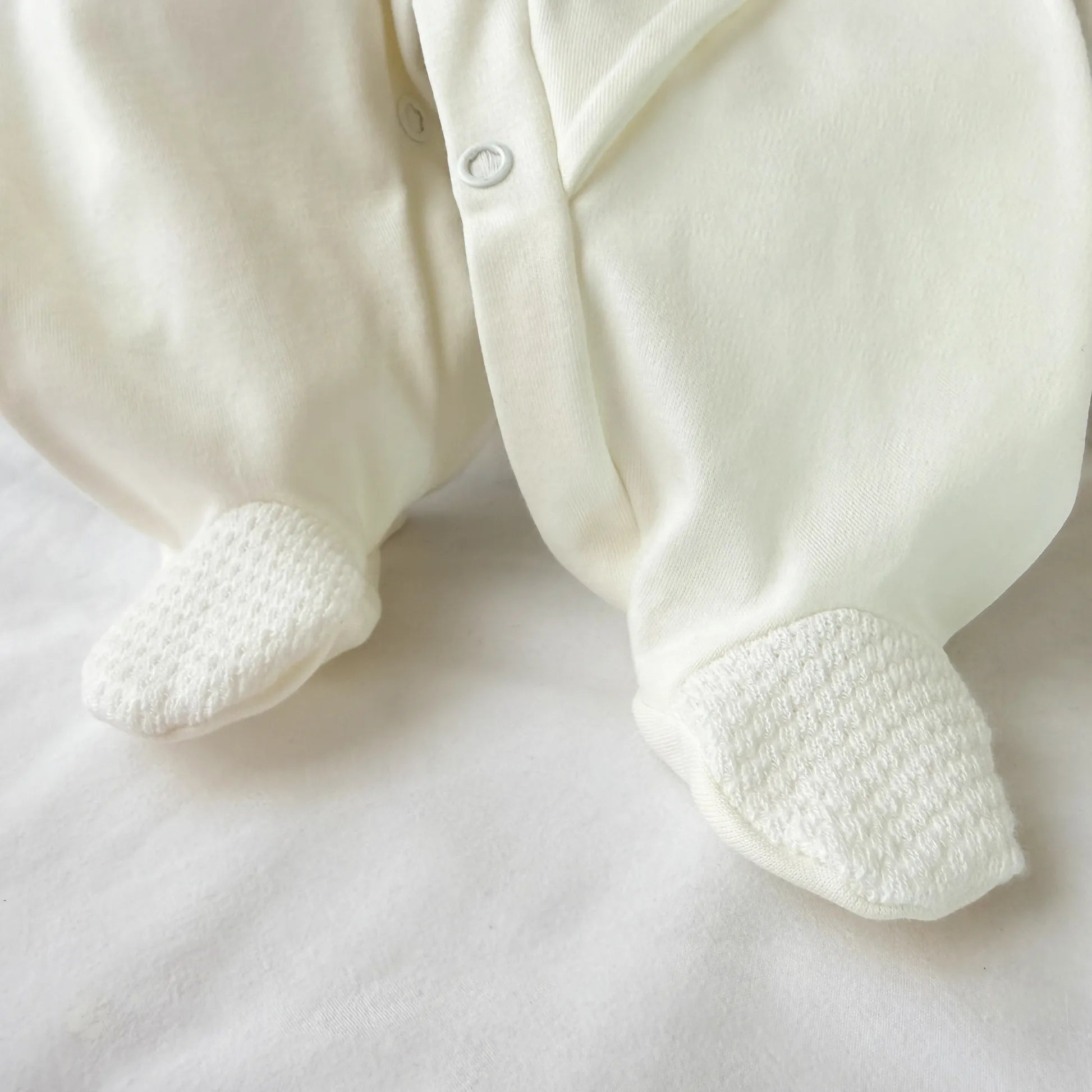 Pormenor de babygrow de algodão com motivo coelhinho e ursinho com livro pérola