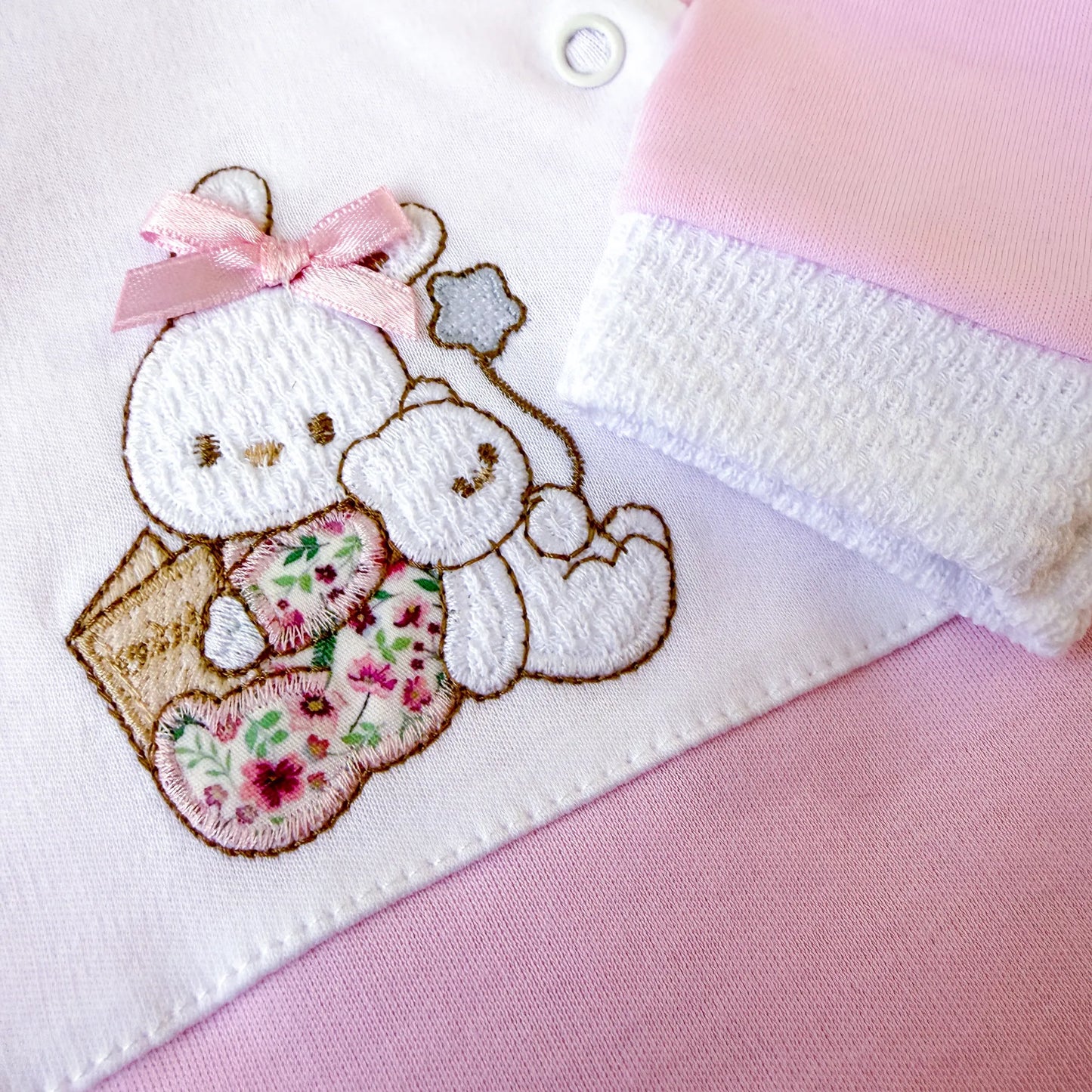 Pormenor de babygrow de algodão com motivo coelhinho e ursinho com livro rosa