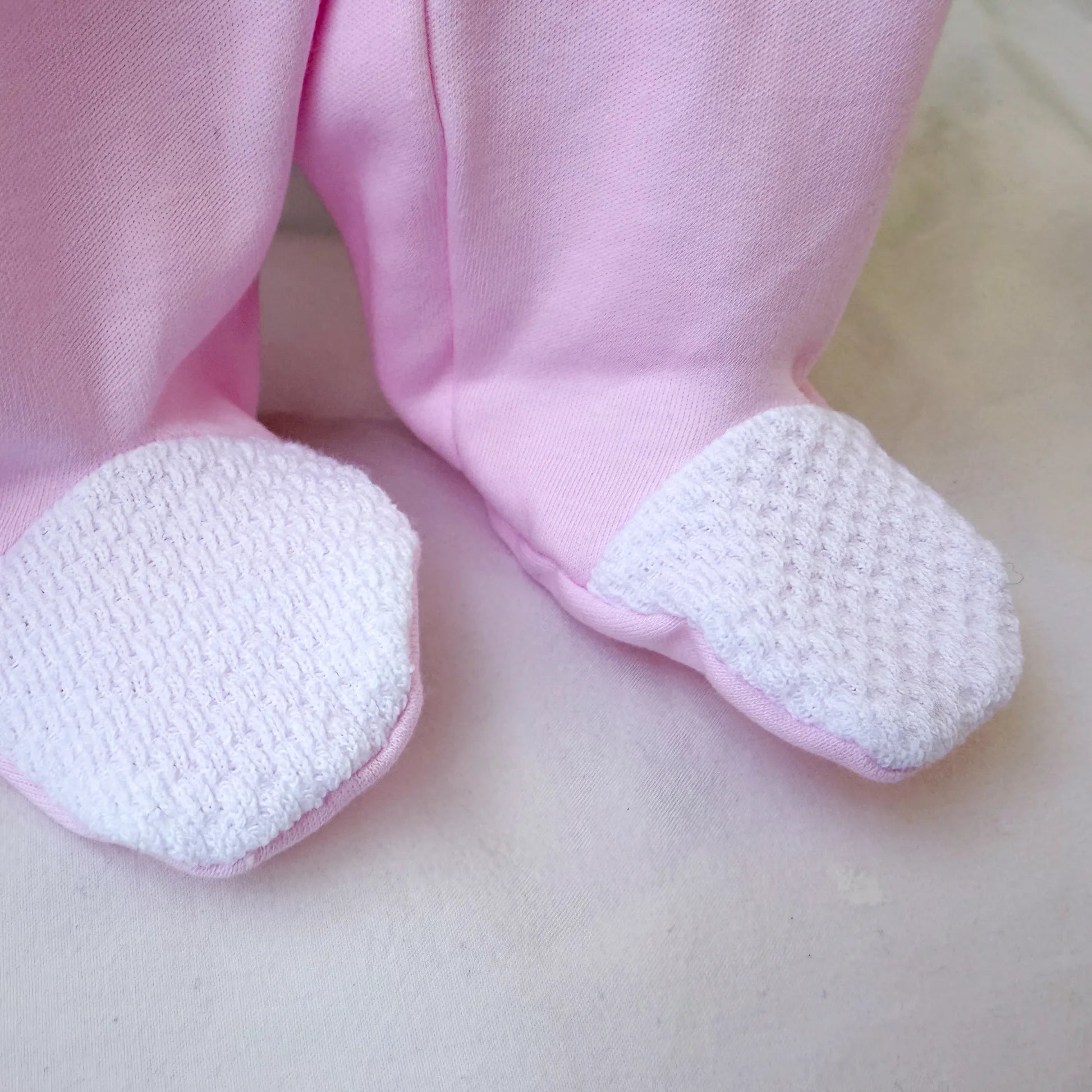 Pormenor de babygrow de algodão com motivo coelhinho e ursinho com livro rosa