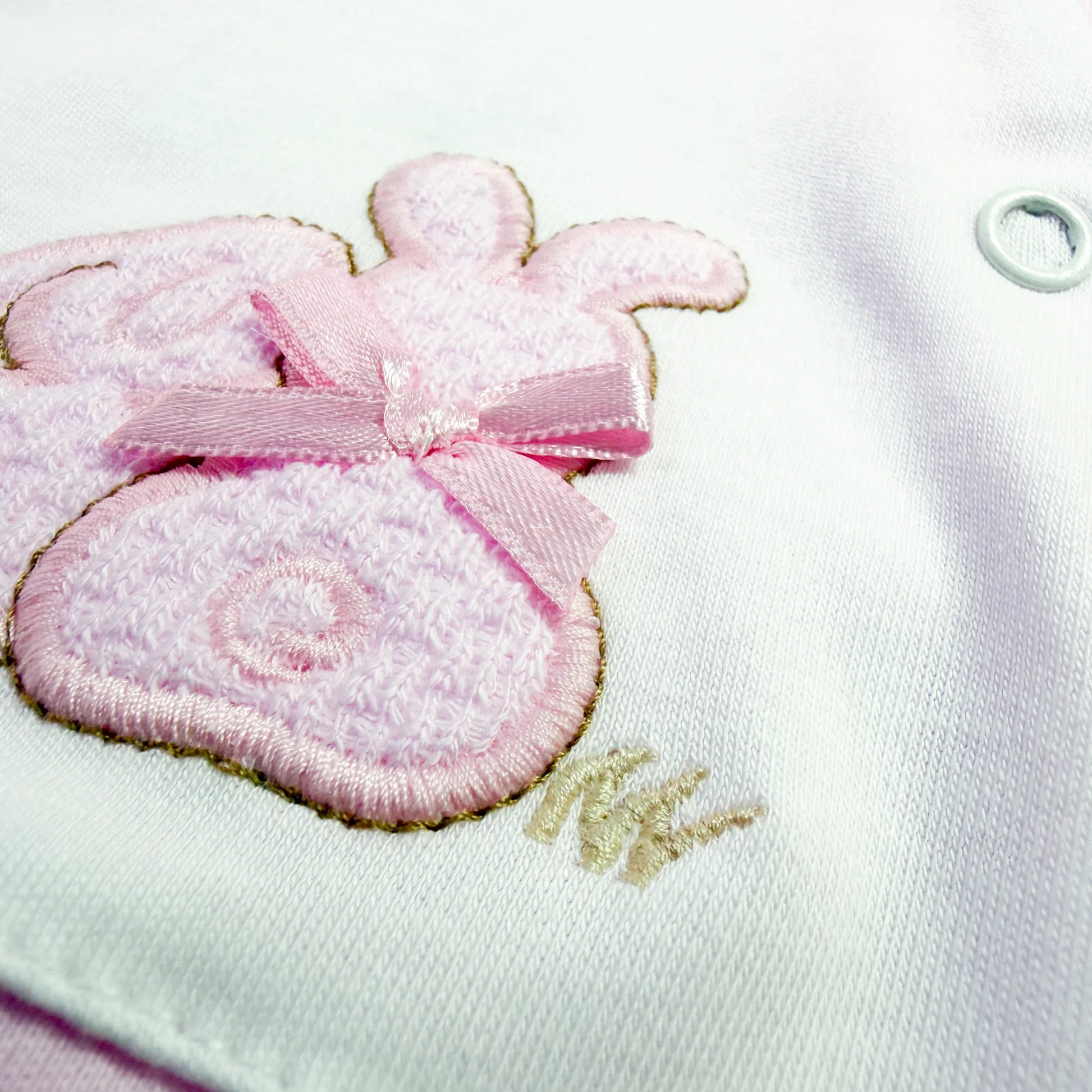 Pormenor de babygrow de algodão com motivo coelhos tricot com lacinho rosa