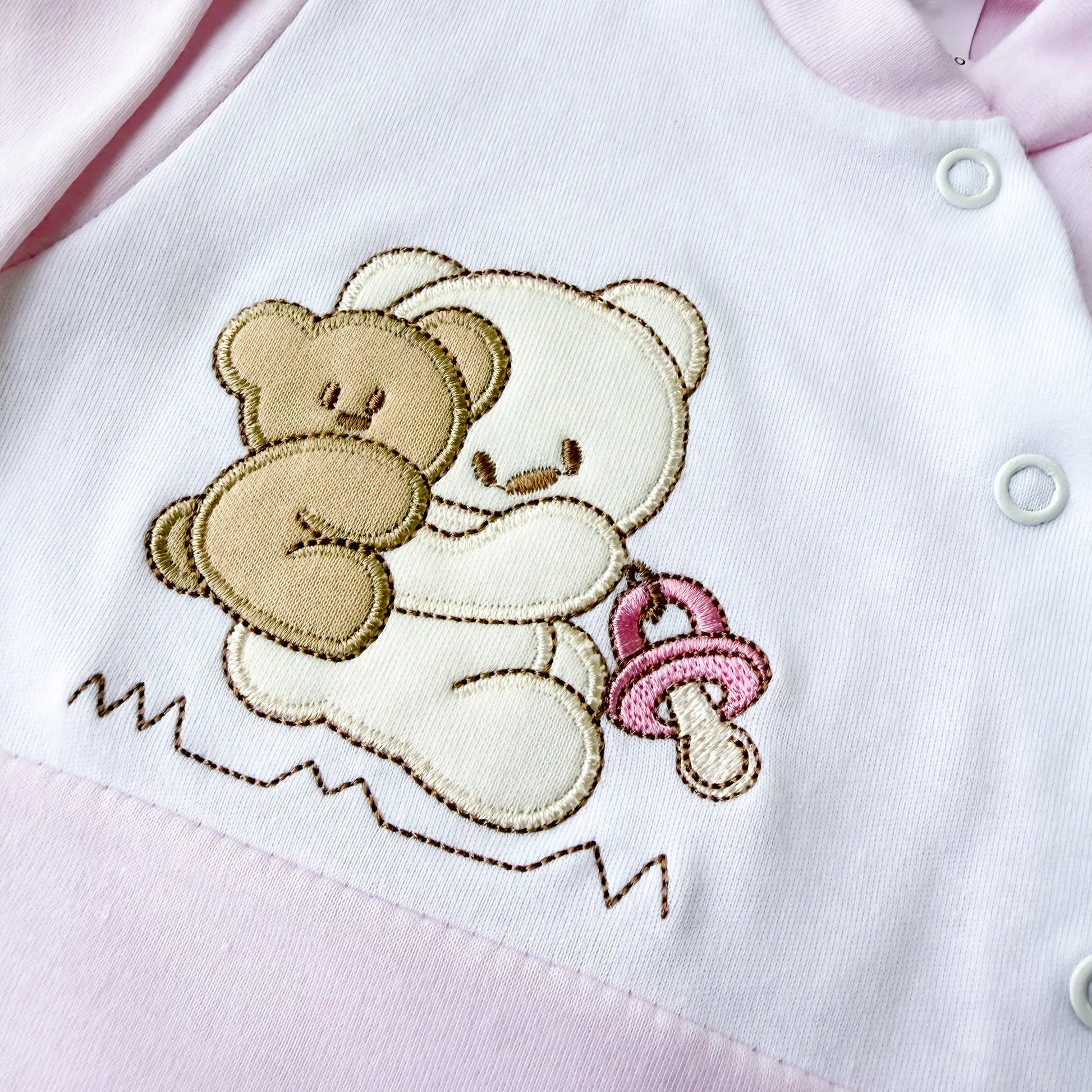 Pormenor de babygrow de algodão com motivo ursinho às cavalitas rosa