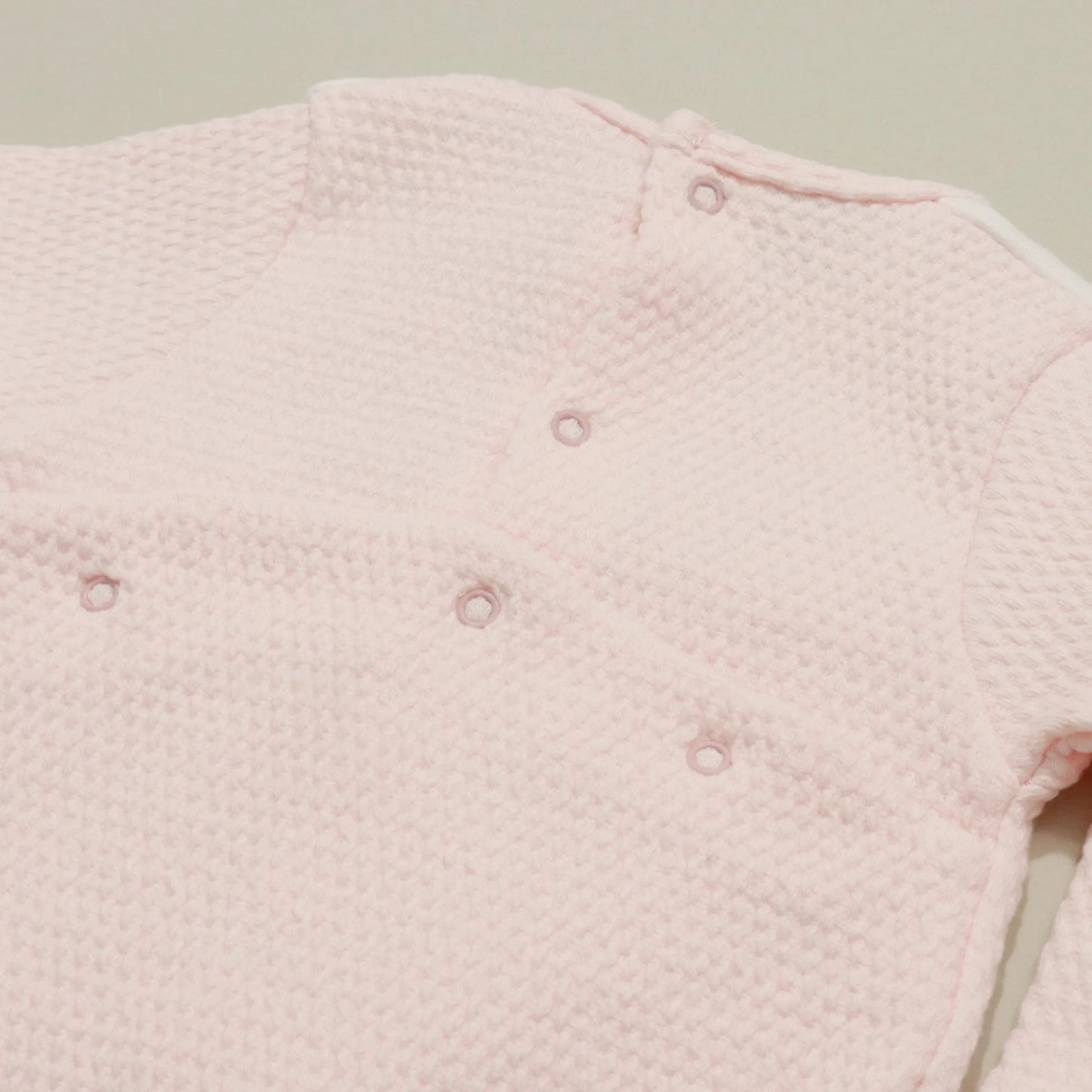 Pormenor de babygrow com efeito renda e lacinho no peito rosa