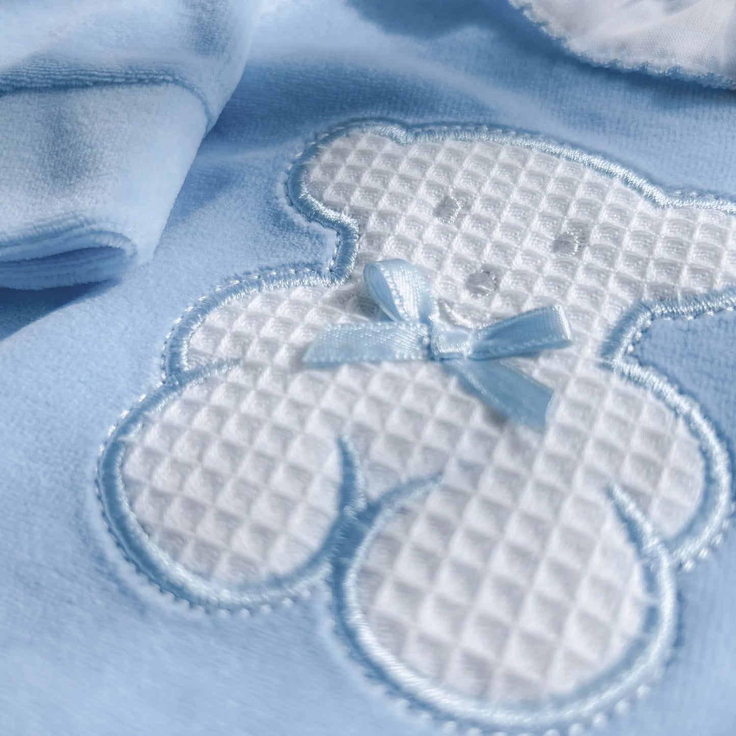 Pormenor de babygrow com gola em folho e motivo ursinho waffle azul