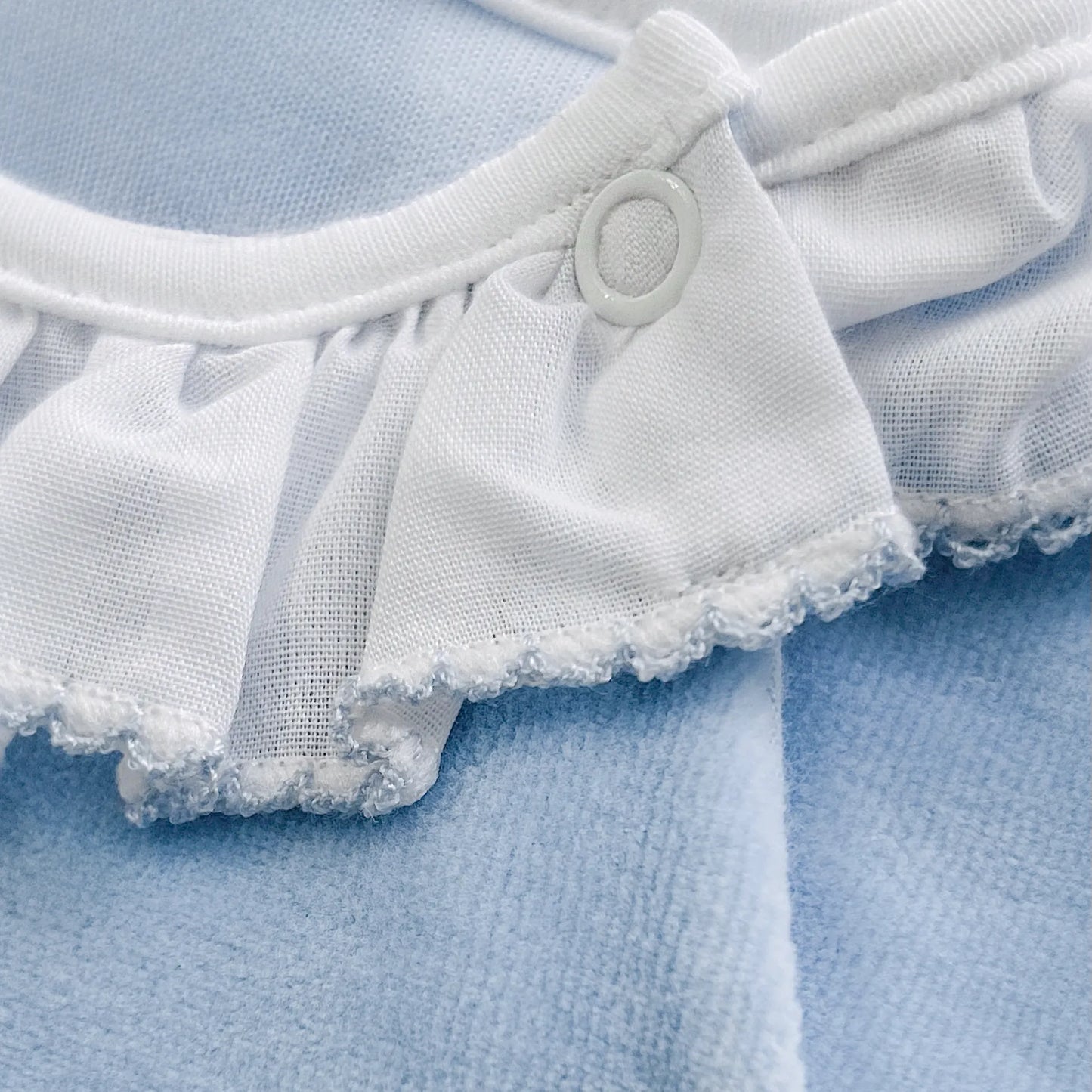 Pormenor de babygrow com gola em folho e motivo ursinho waffle azul