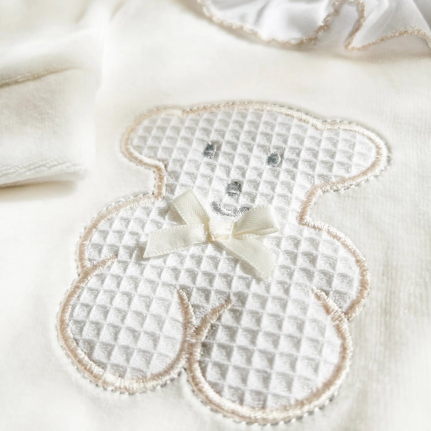 Pormenor de babygrow com gola em folho e motivo ursinho waffle pérola