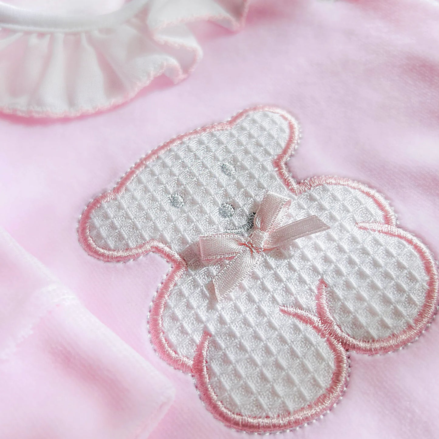 Pormenor de babygrow com gola em folho e motivo ursinho waffle rosa