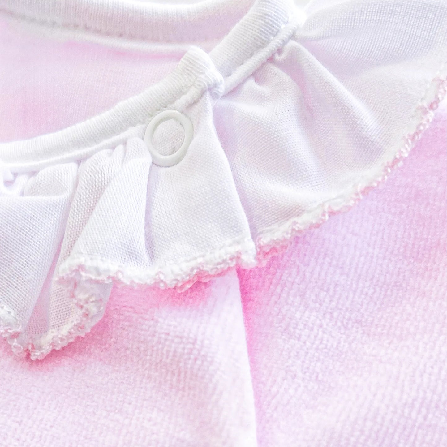 Pormenor de babygrow com gola em folho e motivo ursinho waffle rosa