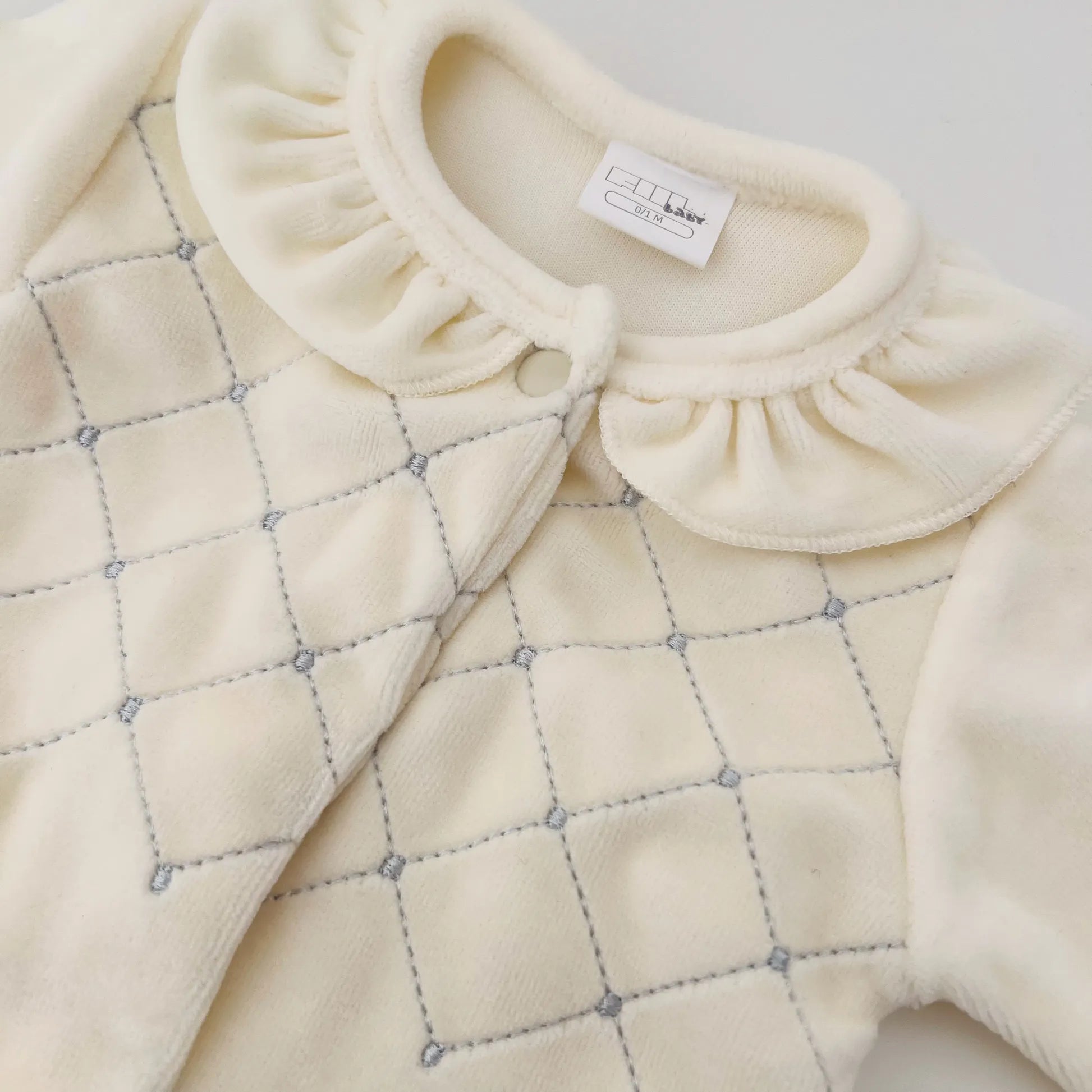 Pormenor de babygrow de menina com gola redonda e bordado losangos pérola