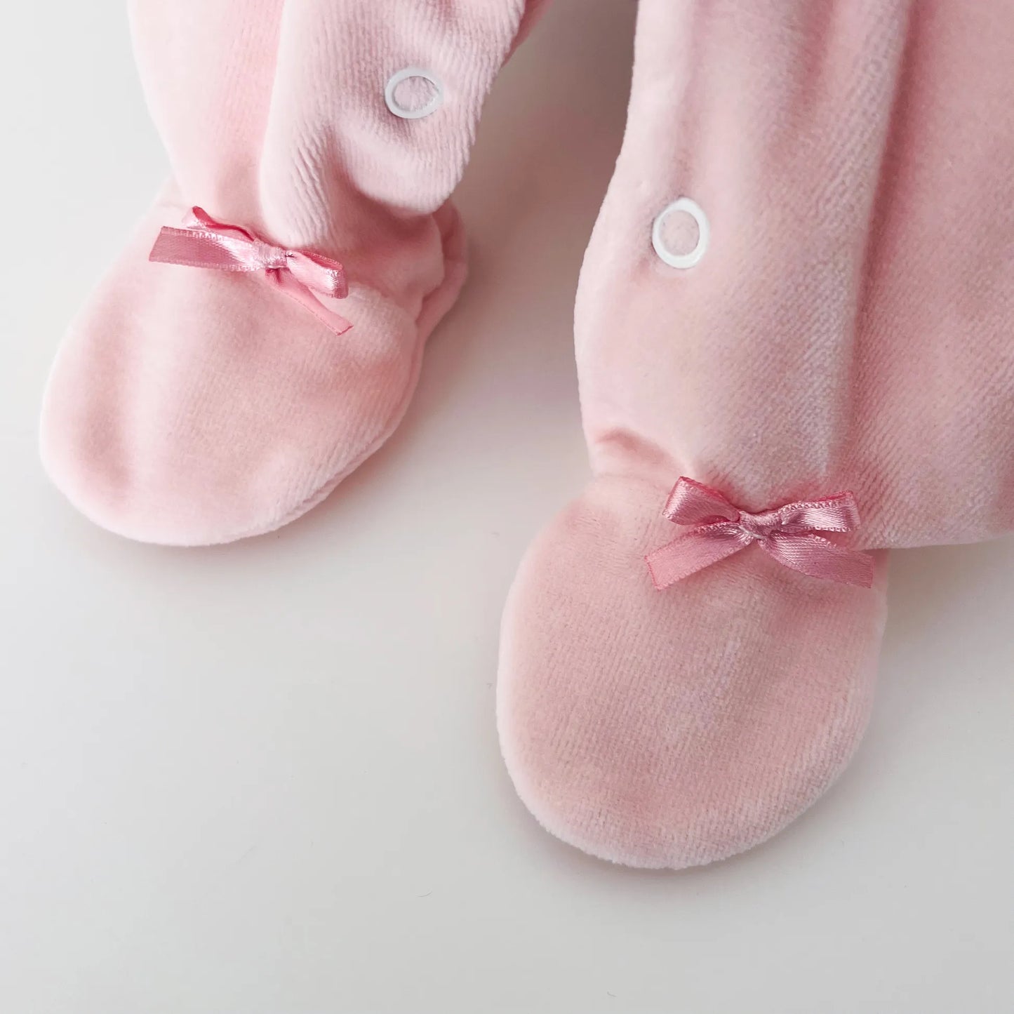 Pormenor de babygrow de menina com gola redonda e bordado losangos rosa