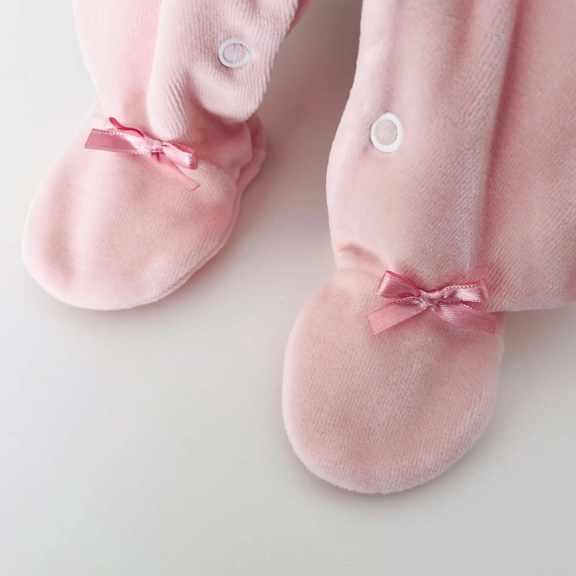 Pormenor de babygrow de menina com gola redonda e bordado losangos rosa