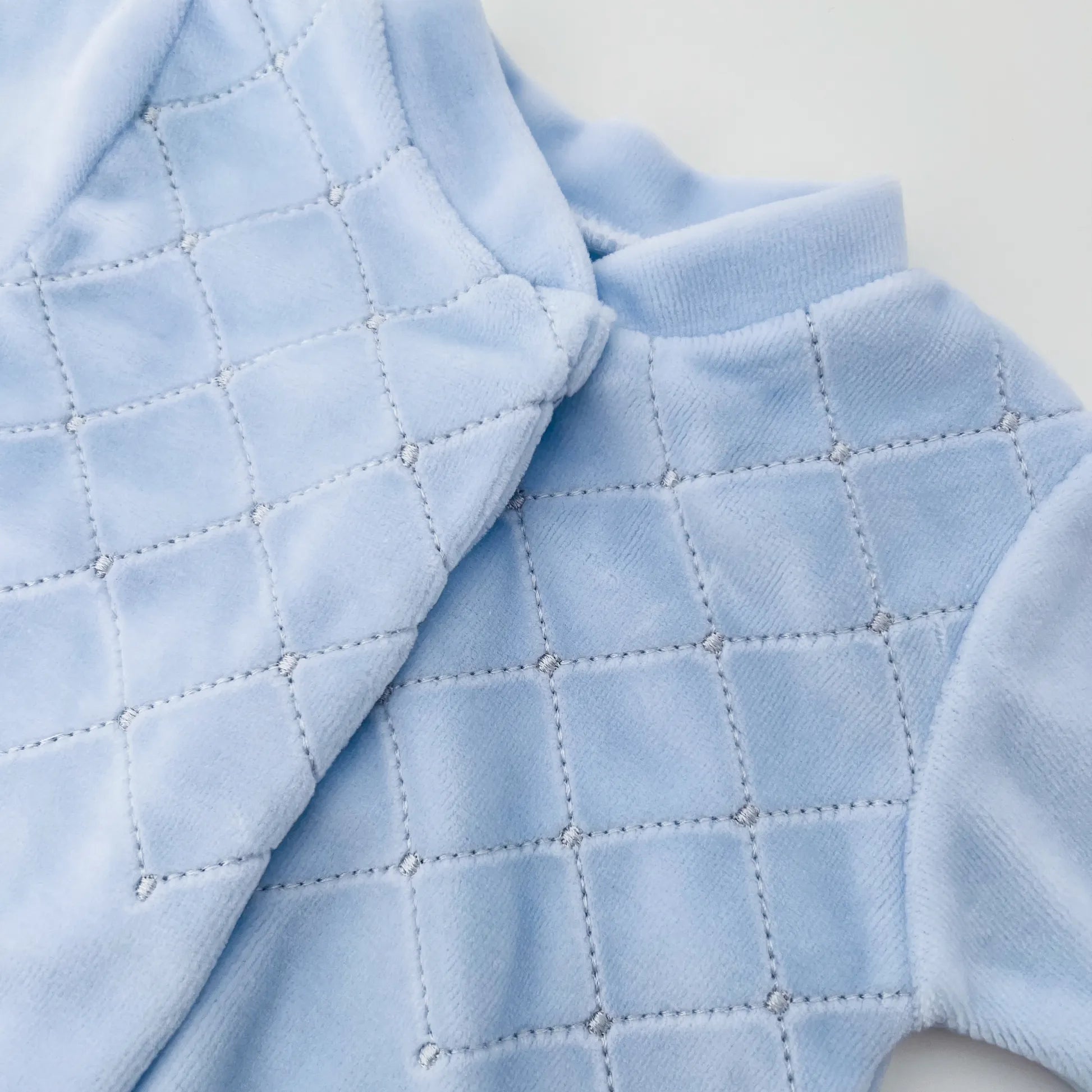Pormenor de babygrow de menino com bordado losangos azul