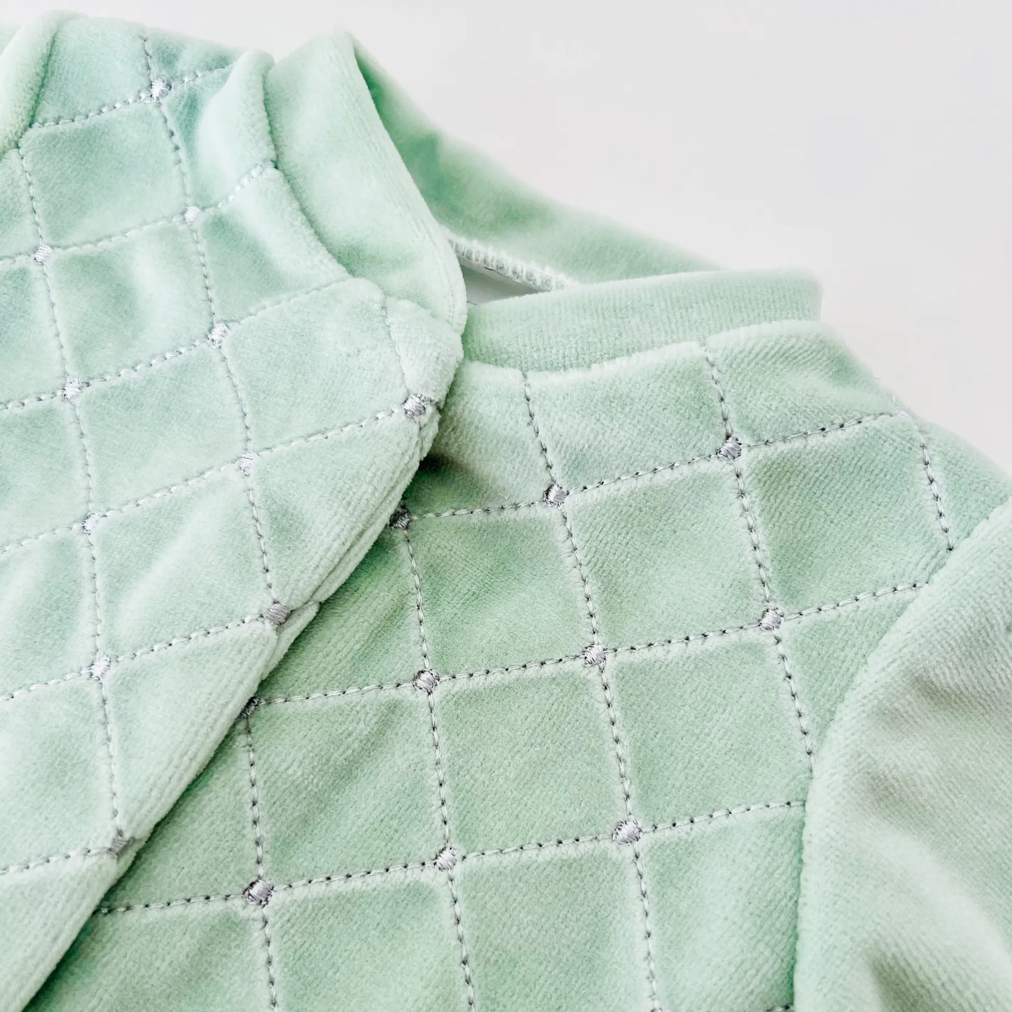 Pormenor de babygrow de menino com bordado losangos verde