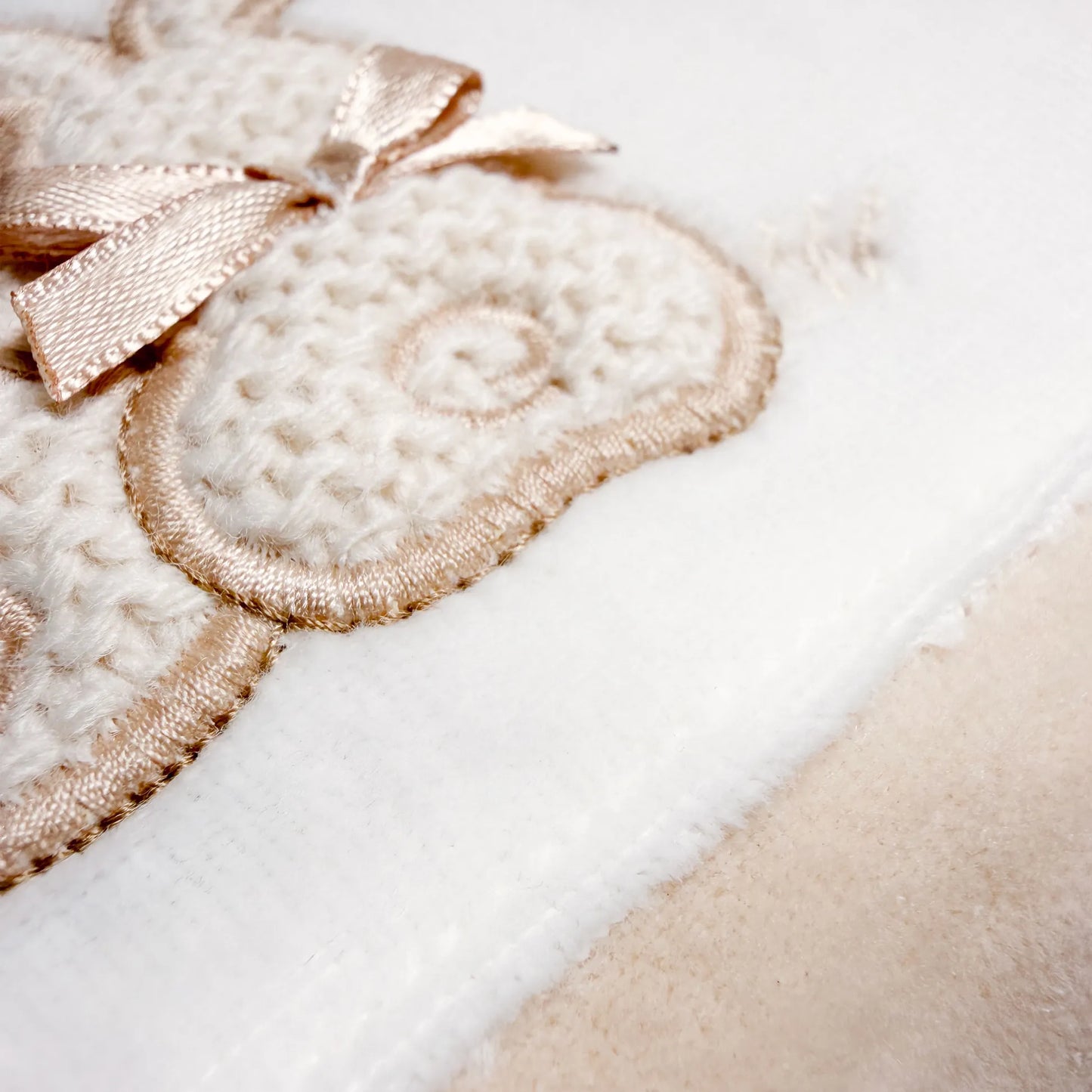 Pormenor de babygrow com motivo coelhos tricot com lacinho bege