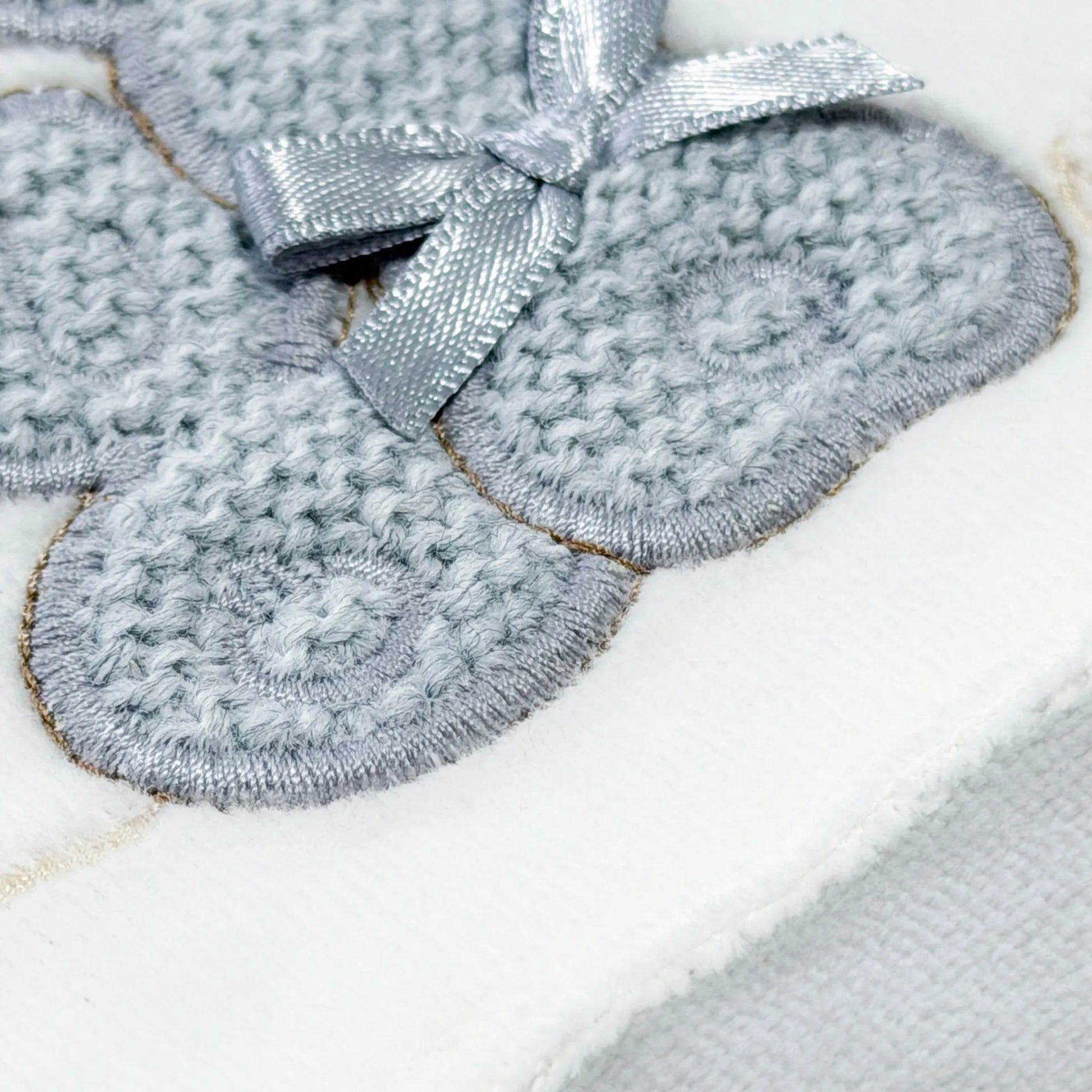 Pormenor de babygrow com motivo coelhos tricot com lacinho cinza