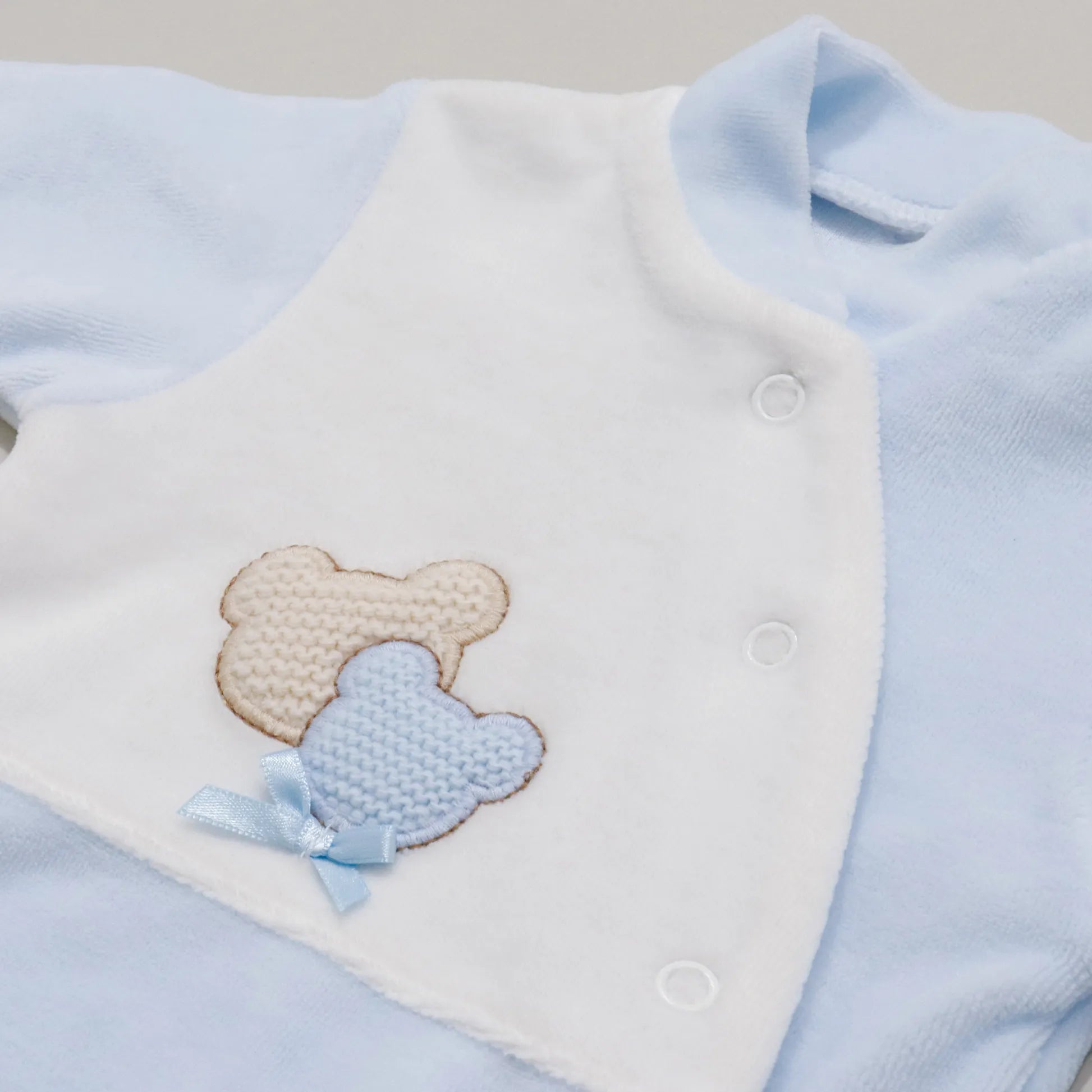 Pormenor de babygrow com motivo ursinhos tricot e lacinho azul