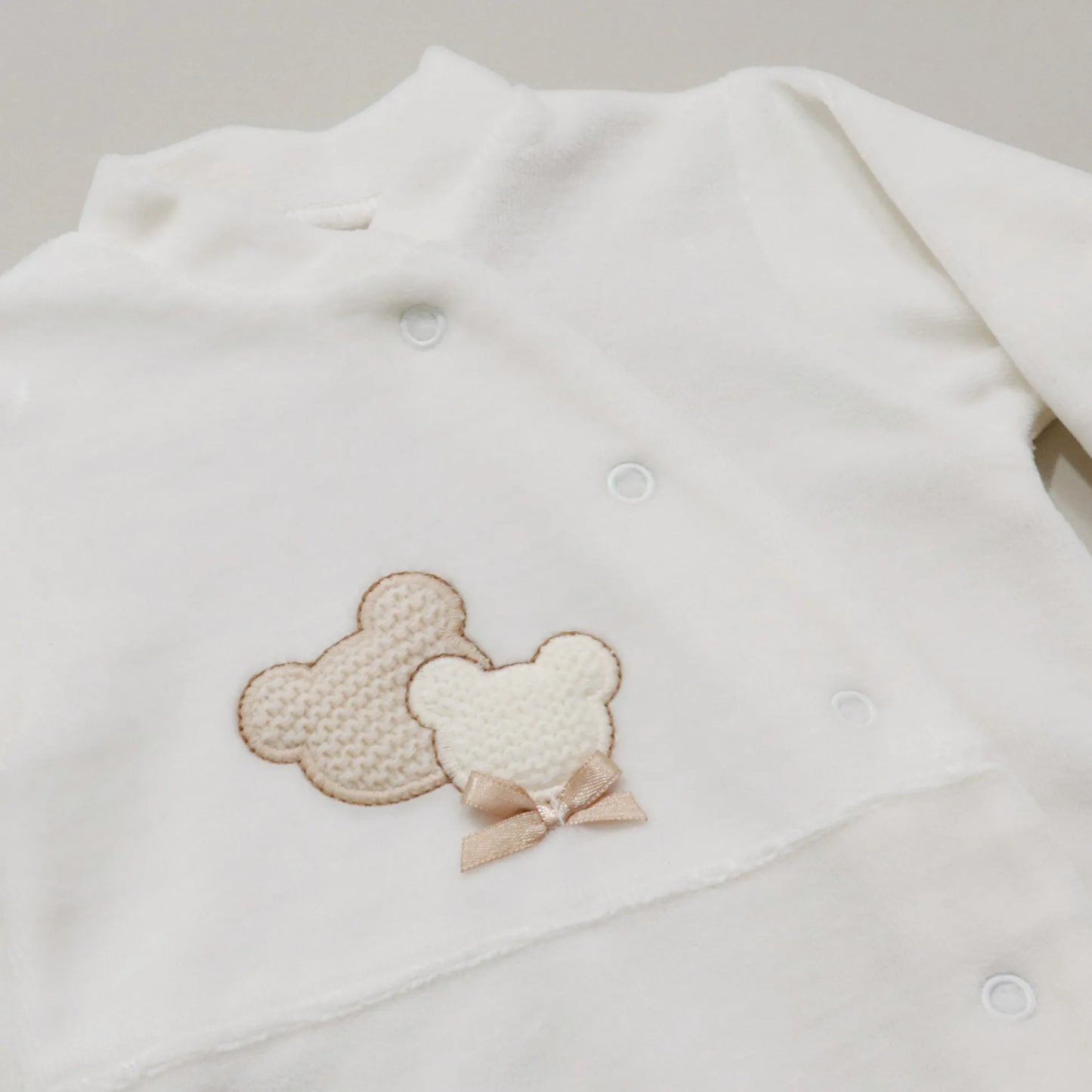 Pormenor de babygrow com motivo ursinhos tricot e lacinho pérola