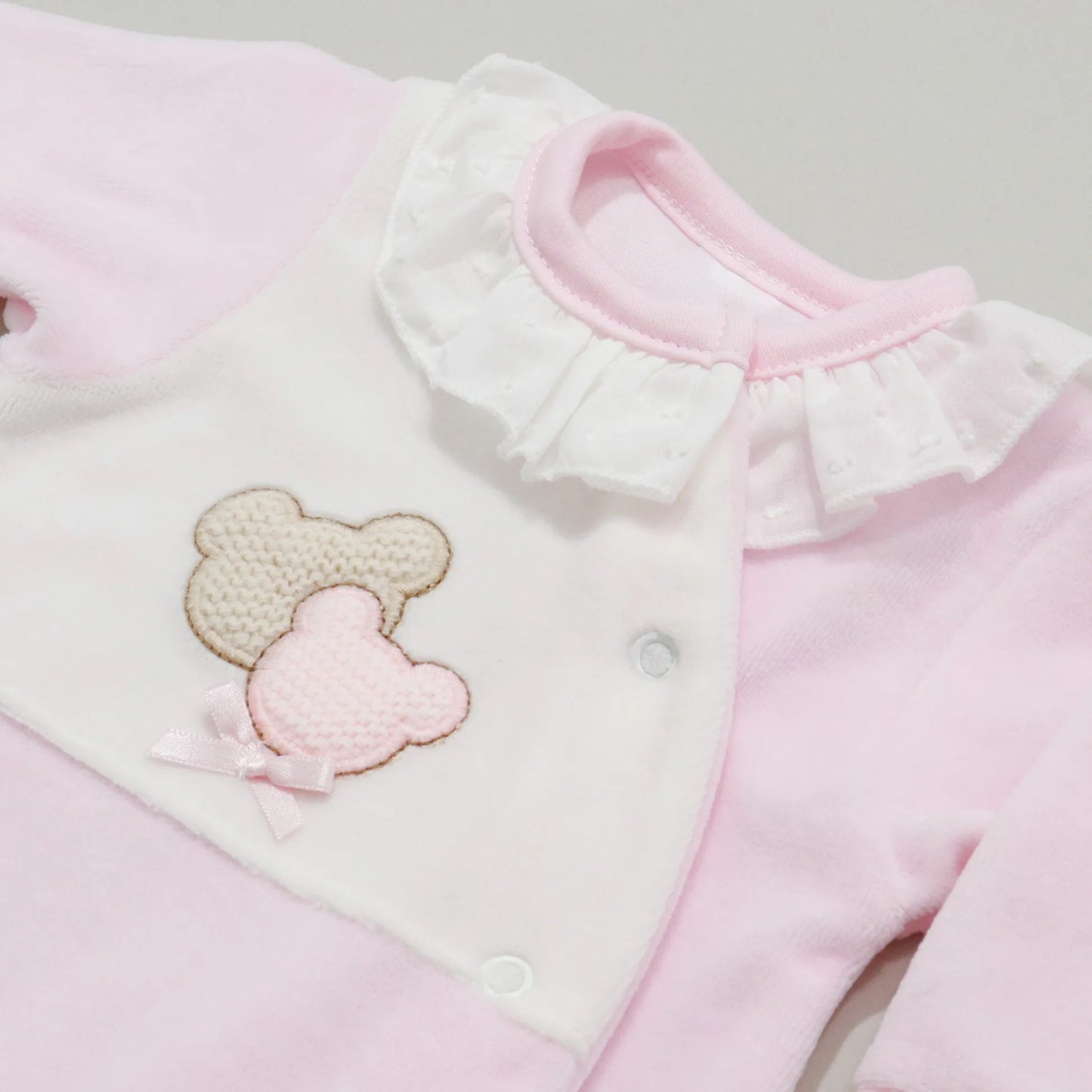 Pormenor de babygrow com motivo ursinhos tricot e lacinho rosa