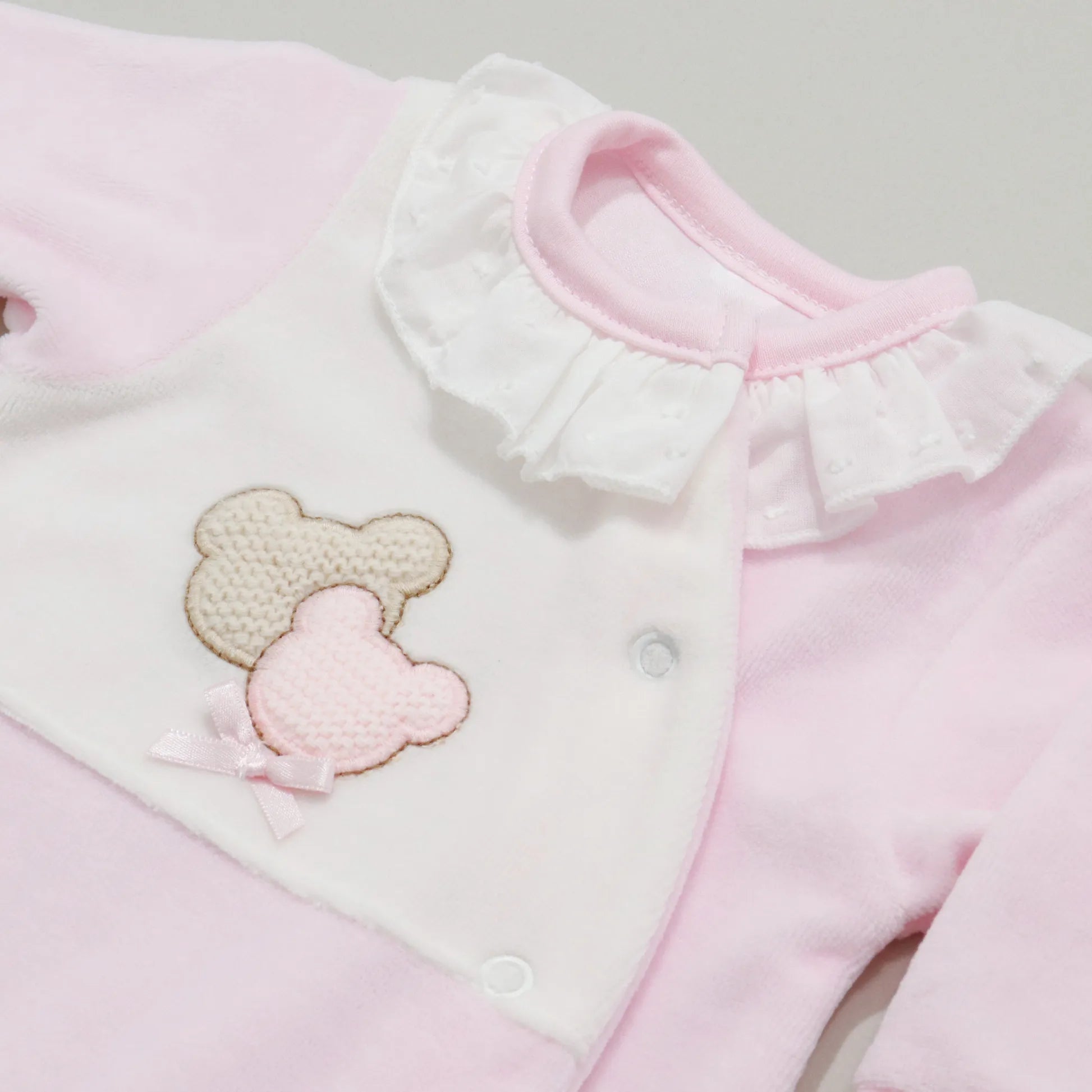 Pormenor de babygrow com motivo ursinhos tricot e lacinho rosa