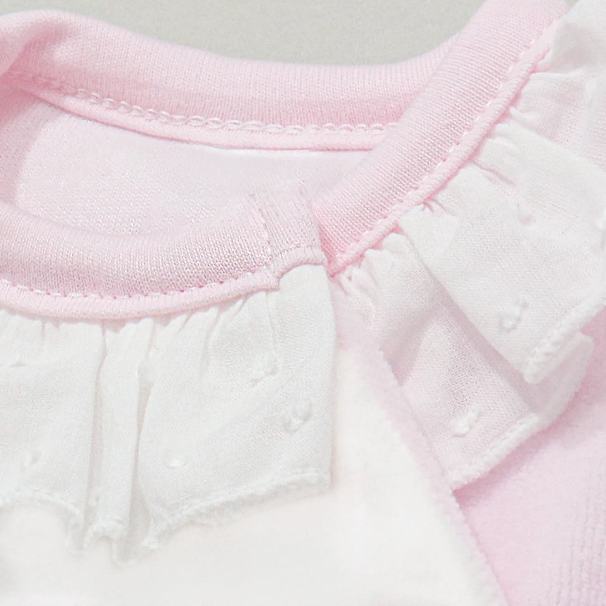 Pormenor de babygrow com motivo ursinhos tricot e lacinho rosa