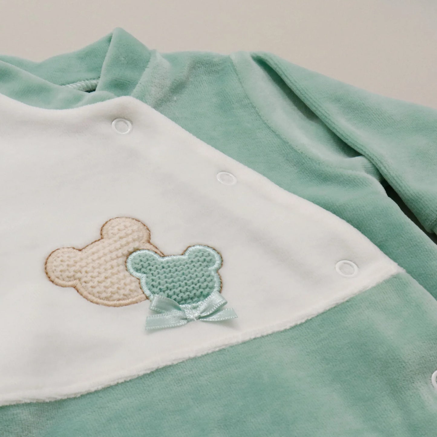 Pormenor de babygrow com motivo ursinhos tricot e lacinho verde