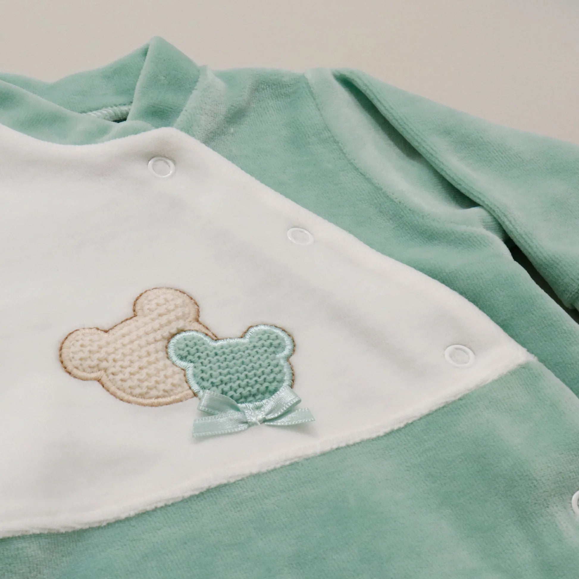 Pormenor de babygrow com motivo ursinhos tricot e lacinho verde